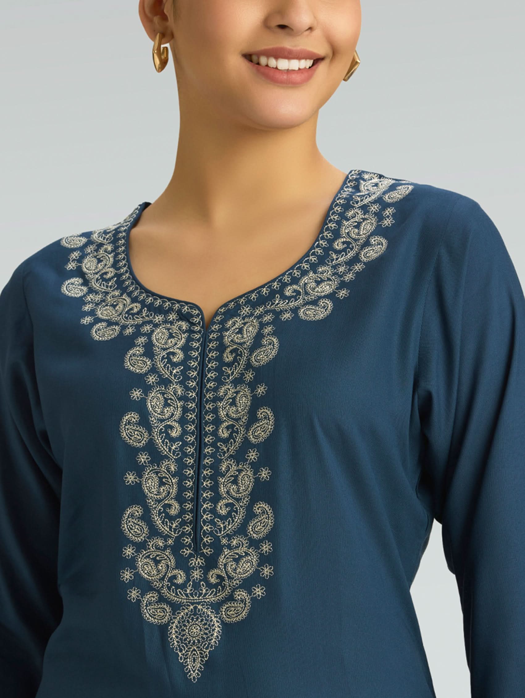Blue embroidered top worn by a model on a plain background