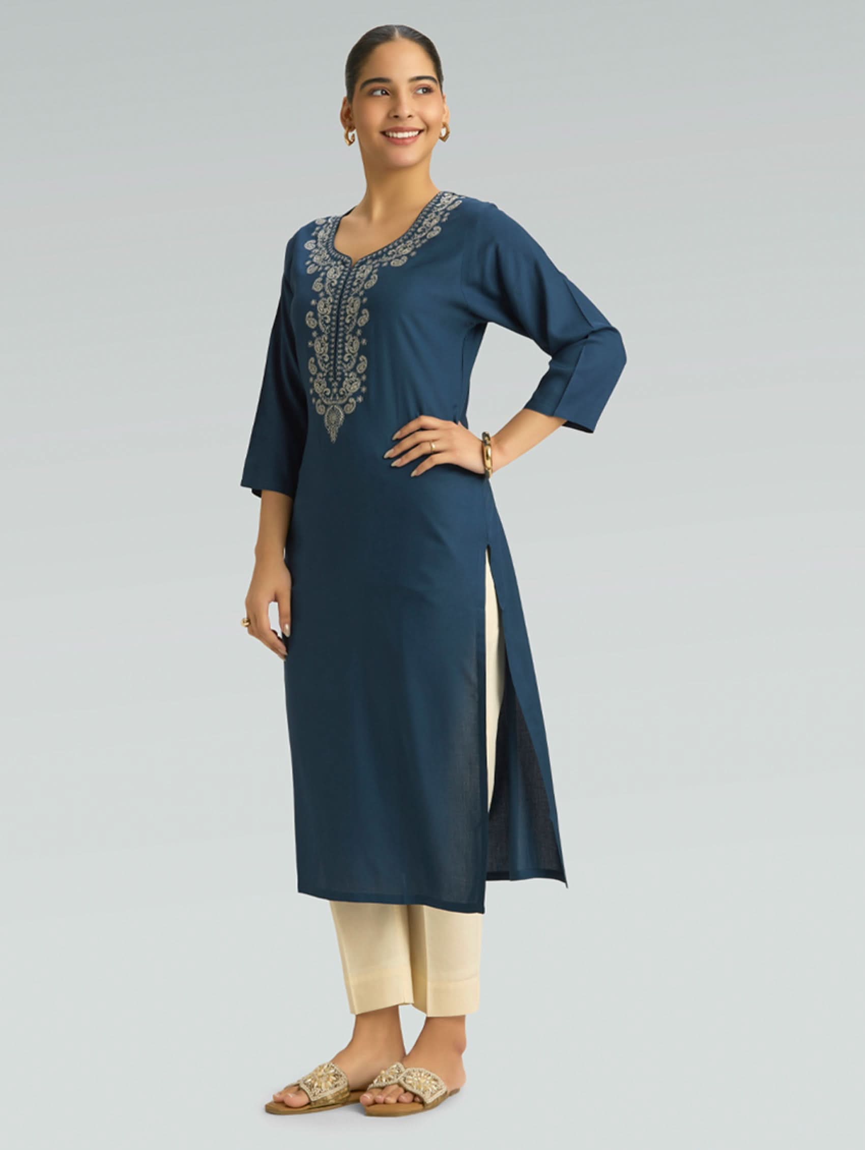 Woman wearing a blue embroidered kurta with beige pants on a gray background