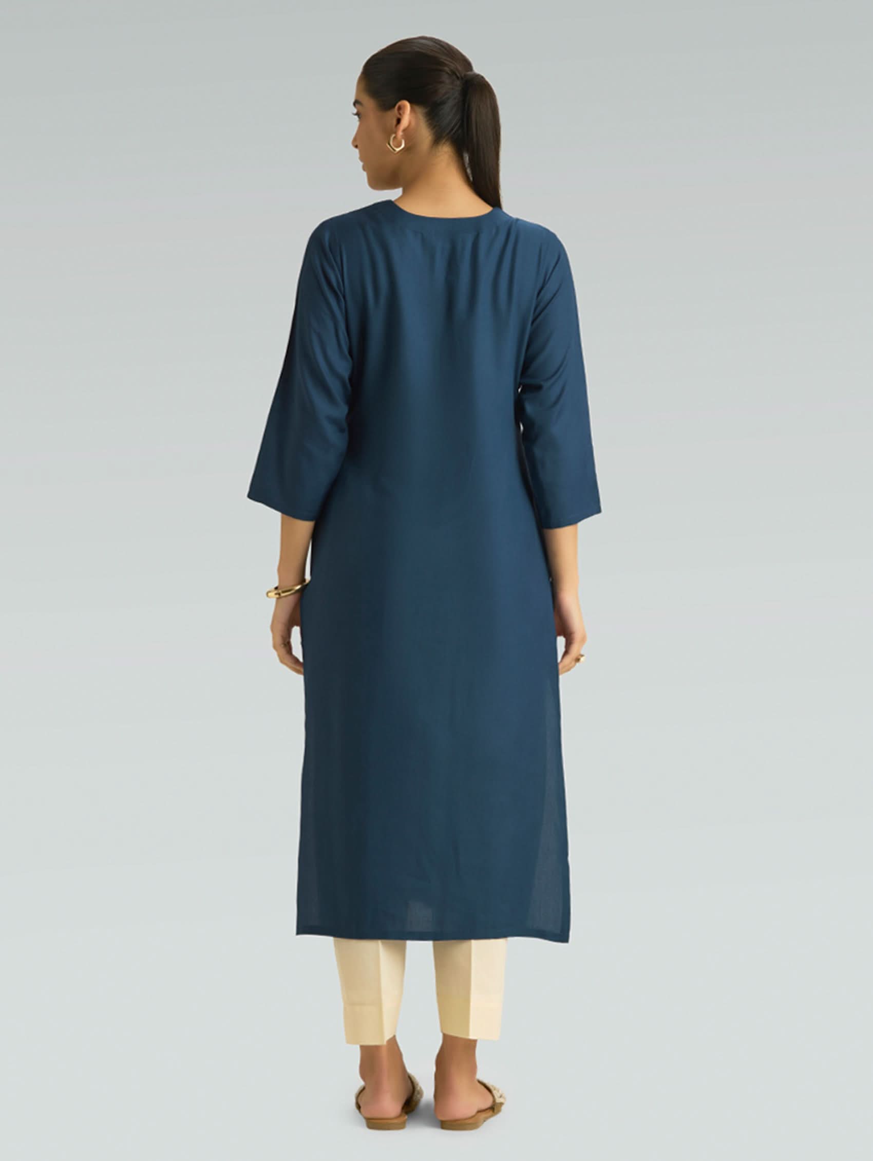 Woman wearing a blue kurta with beige pants on a gray background