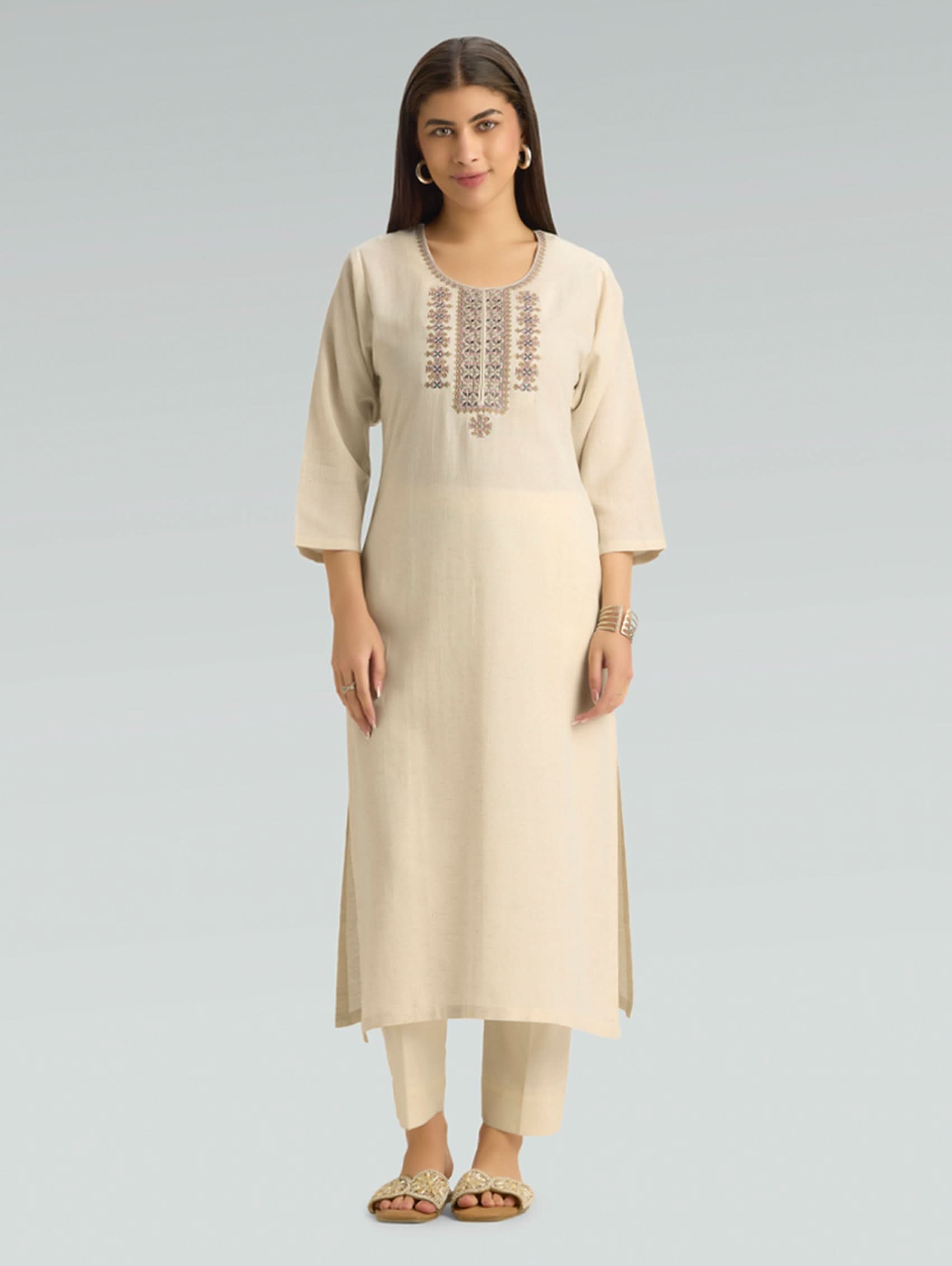 Woman wearing a beige kurta with embroidery on a light gray background