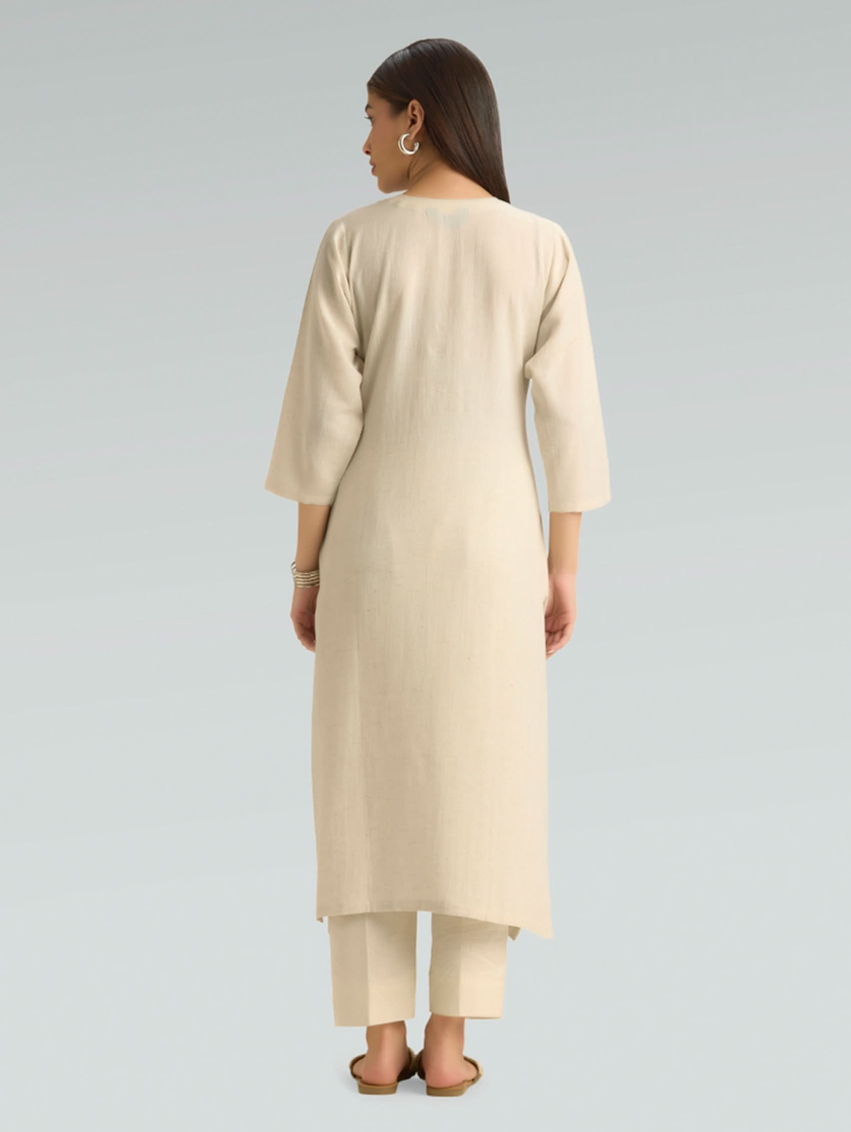 Woman wearing a beige kurta with pants on a gray background