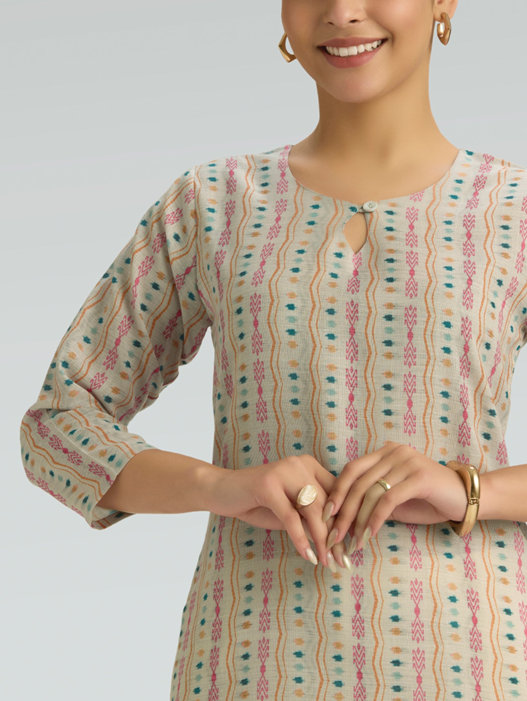 Woman wearing a patterned kurta against a plain background