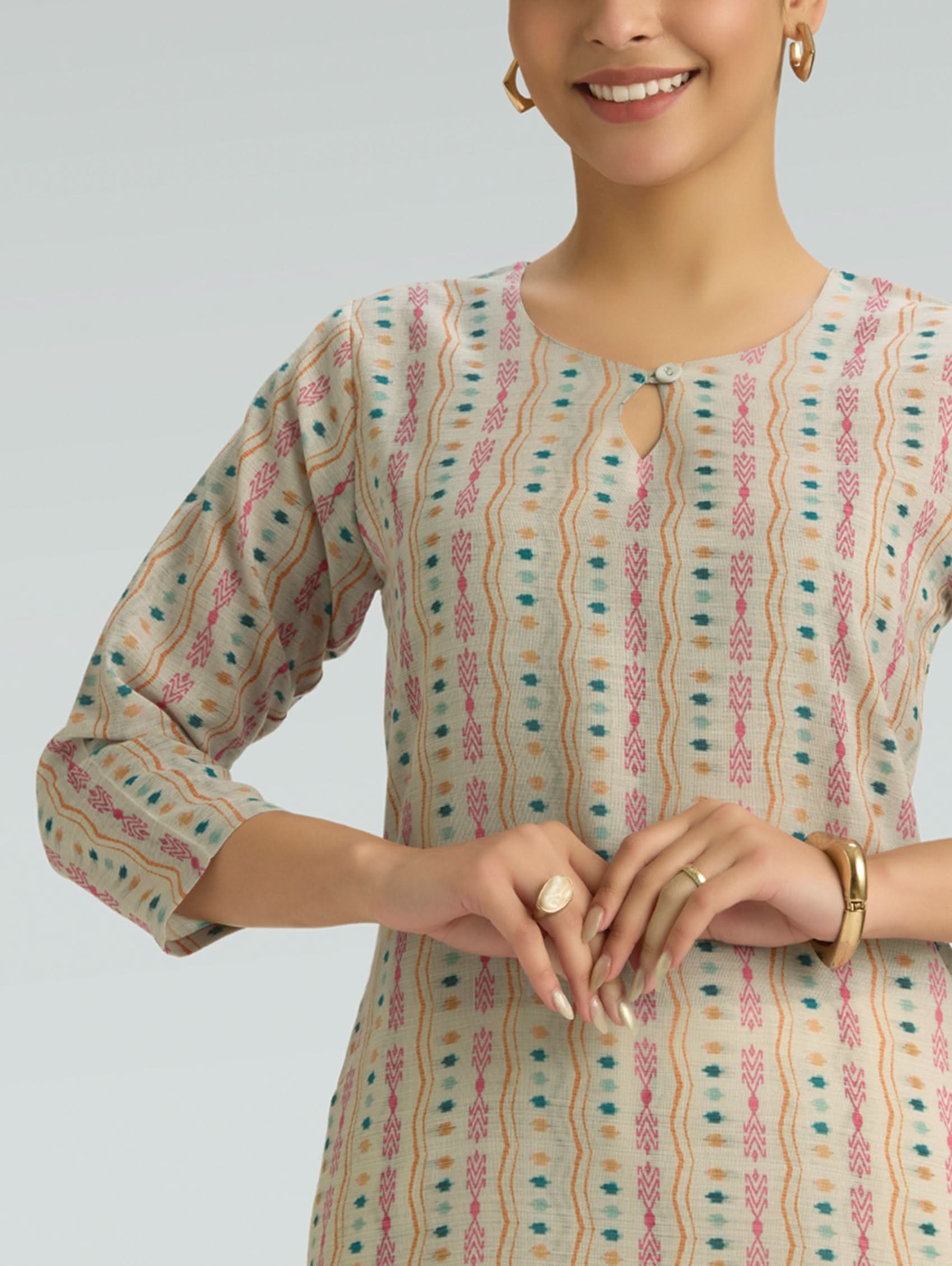 Woman wearing a patterned kurta against a plain background