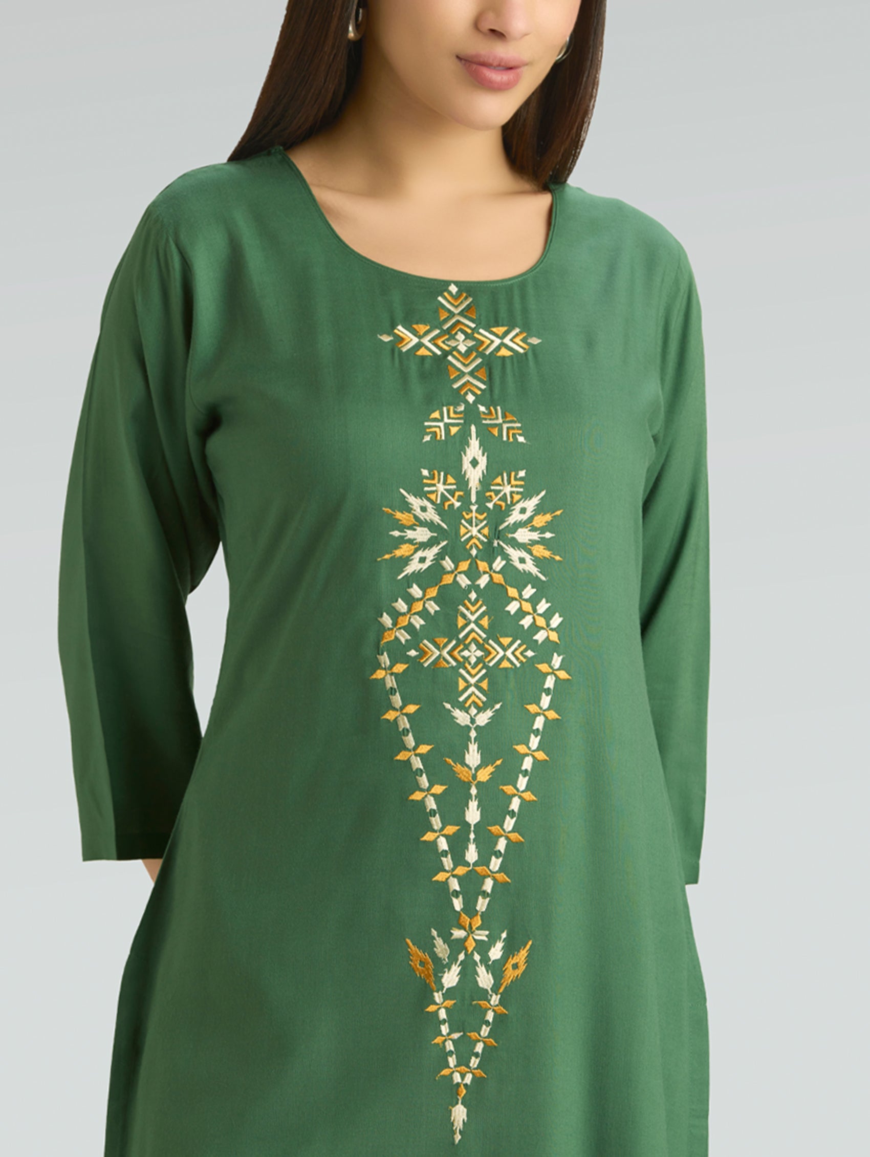 Green dress with gold embroidery on a plain background