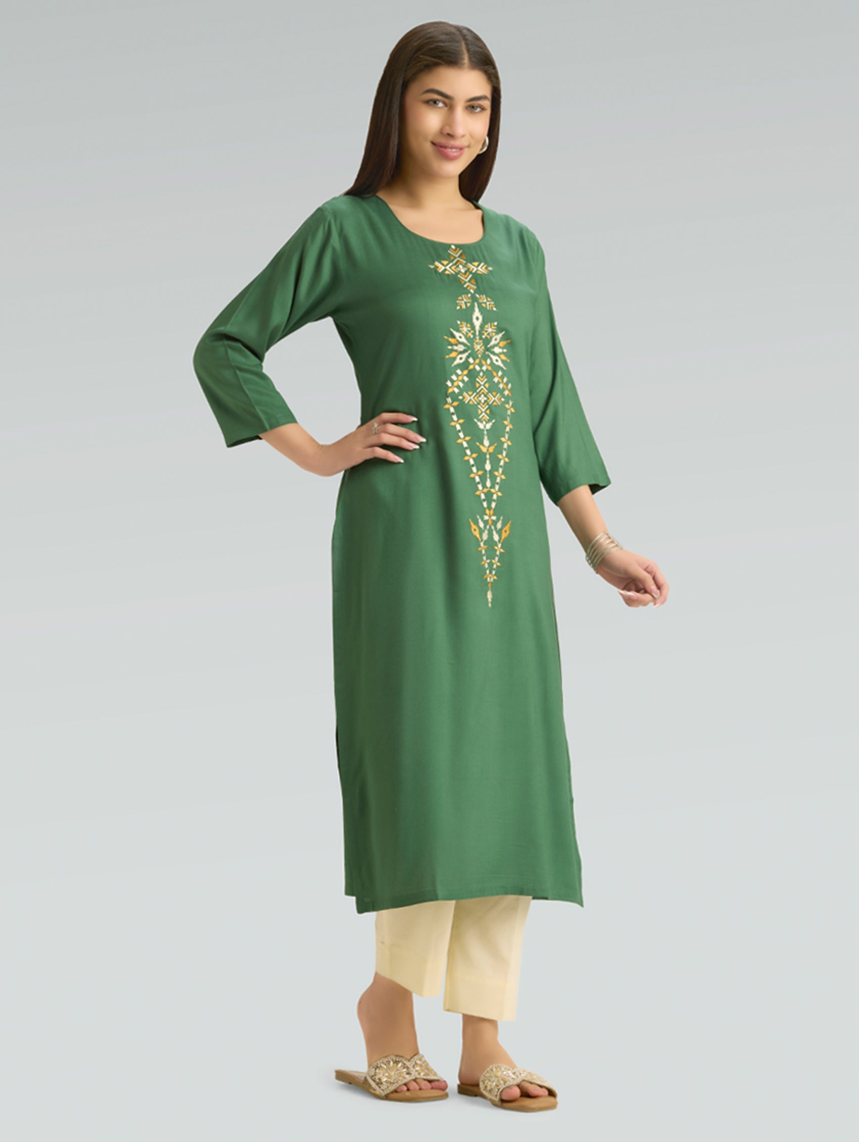 Woman wearing a green kurta with gold embroidery on a gray background