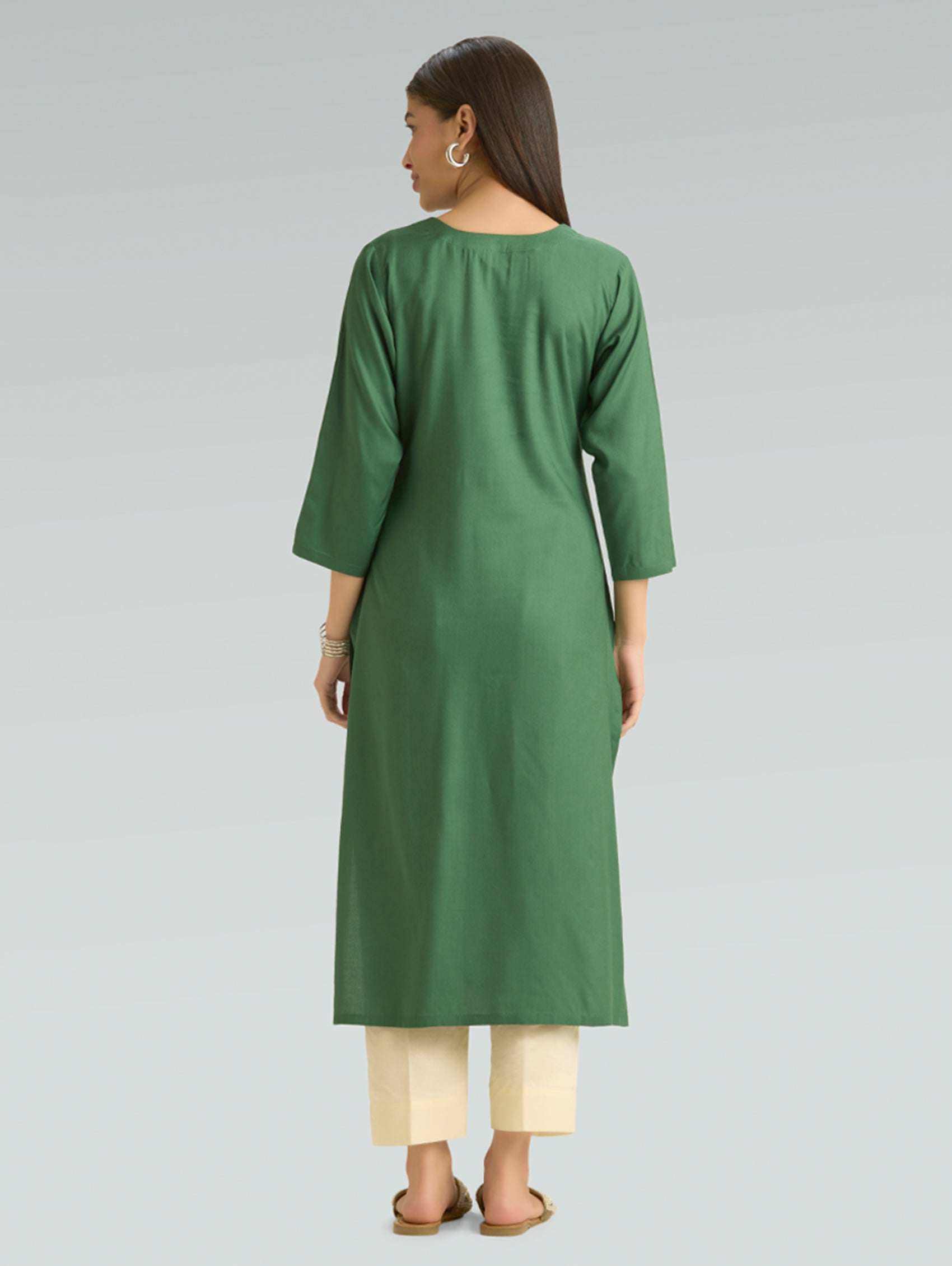 Woman wearing a green kurta with beige pants on a gray background