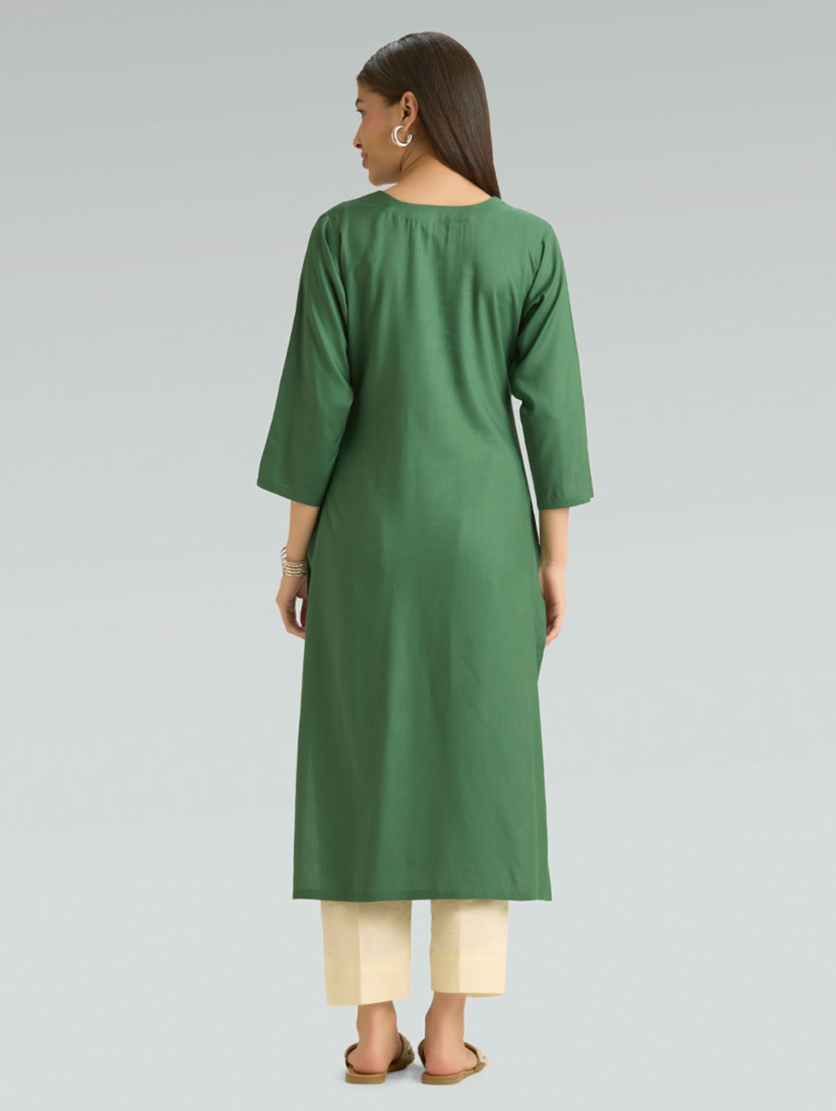 Woman wearing a green kurta with beige pants on a gray background