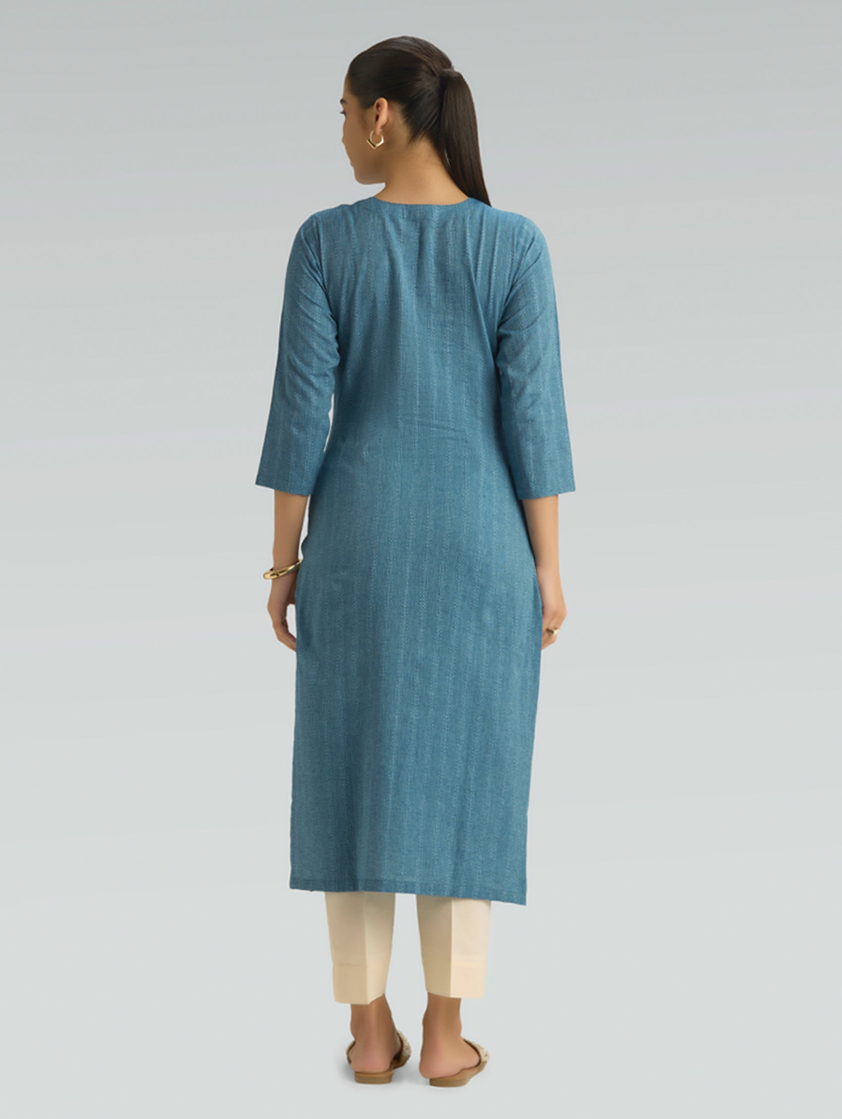 Woman wearing a blue kurta with beige pants on a light gray background