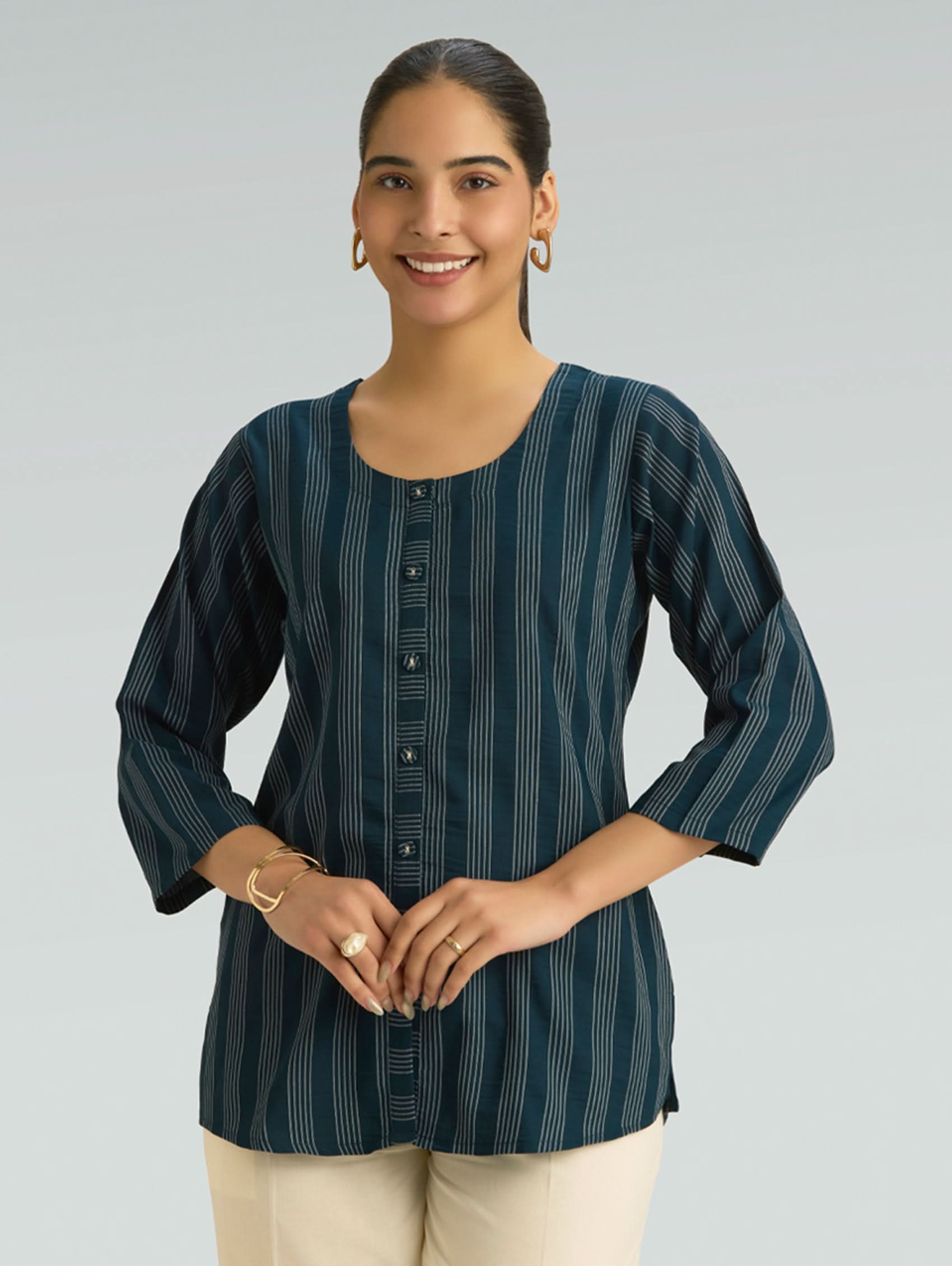 Woman wearing a dark green striped shirt with buttons on a gray background