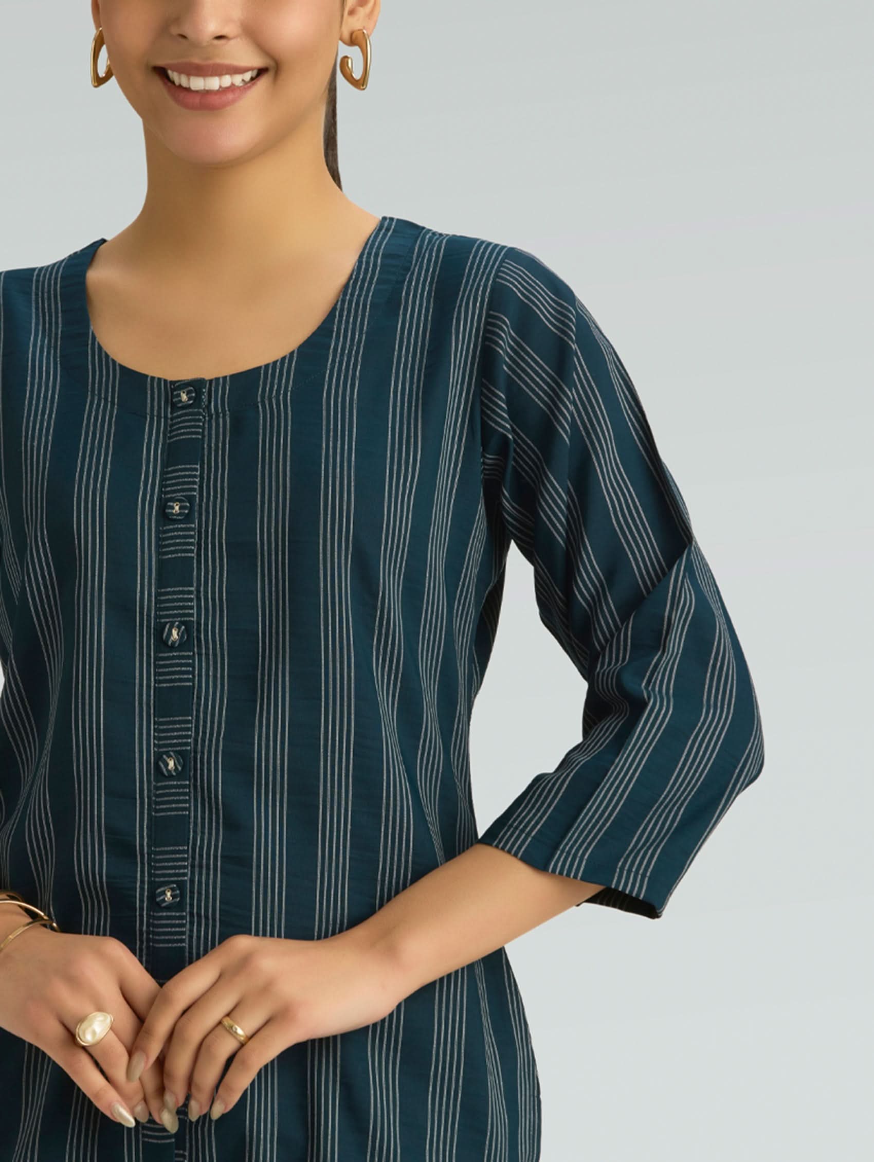 Woman wearing a dark green striped shirt with buttons on a gray background