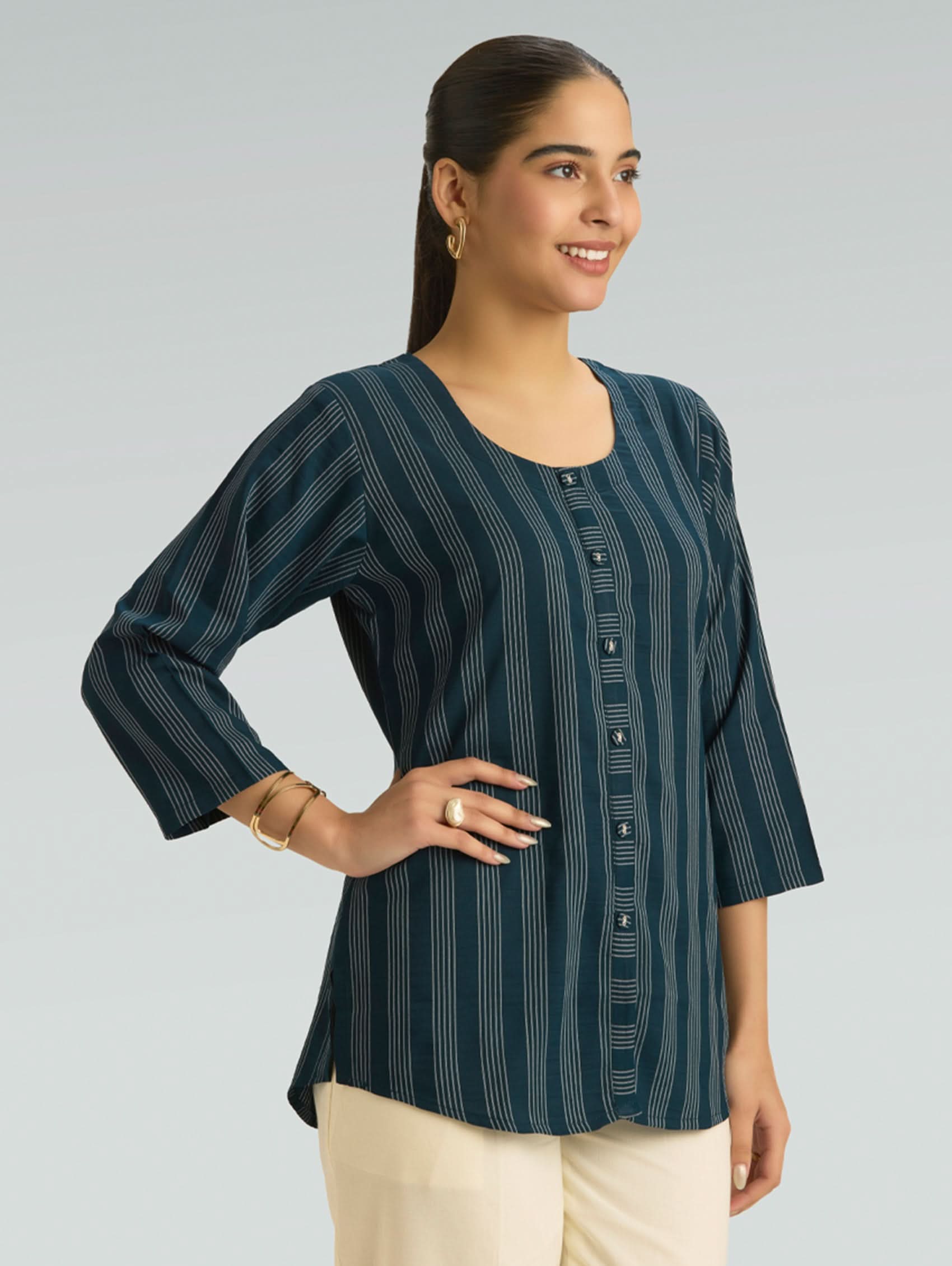 Woman wearing a dark green striped shirt with buttons on a gray background