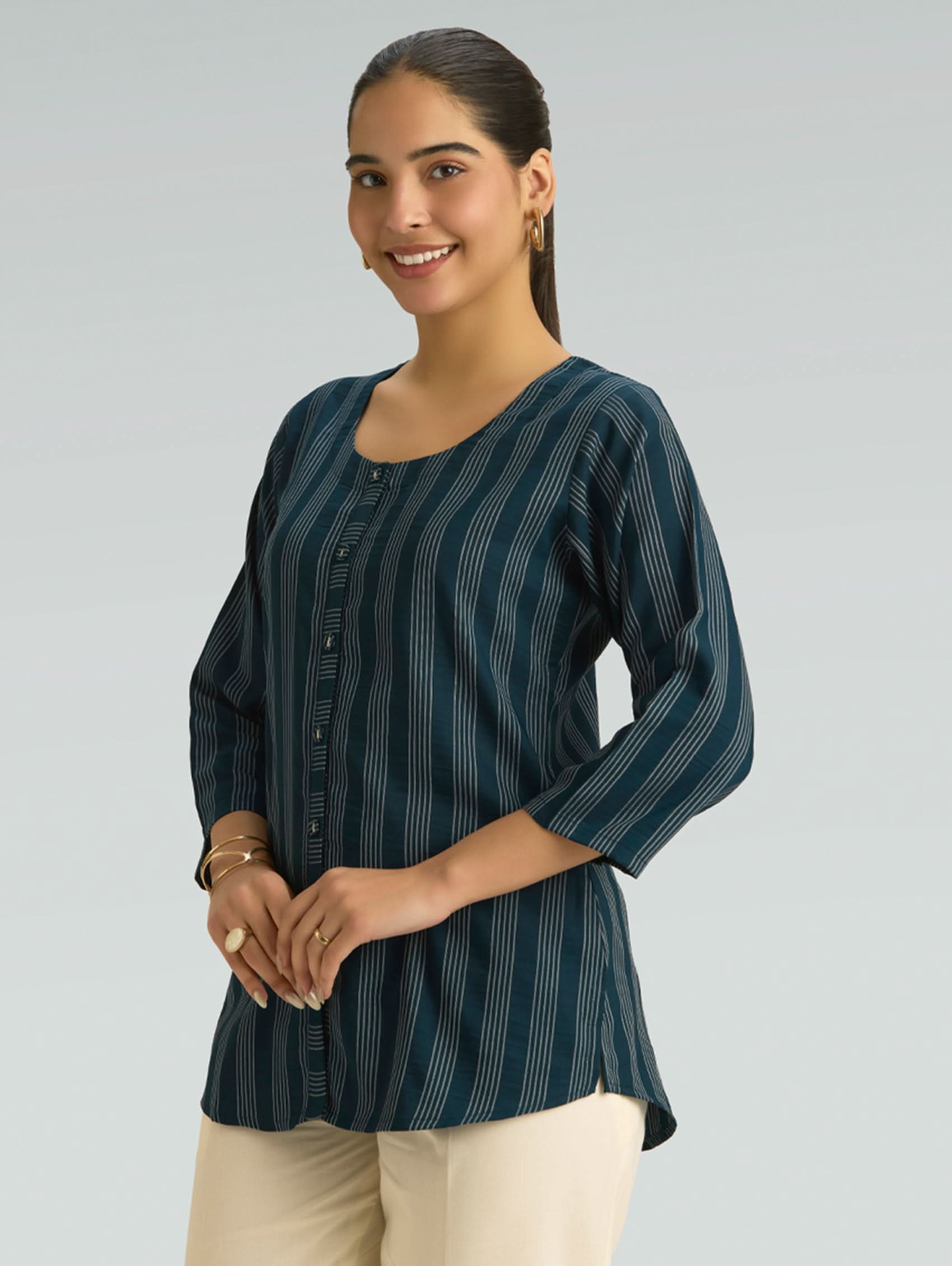 Woman wearing a dark green striped shirt with buttons on a gray background