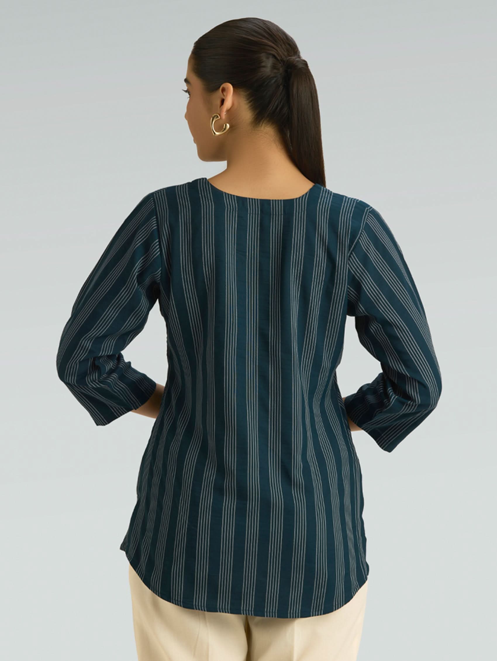Woman wearing a dark green striped shirt with buttons on a gray background
