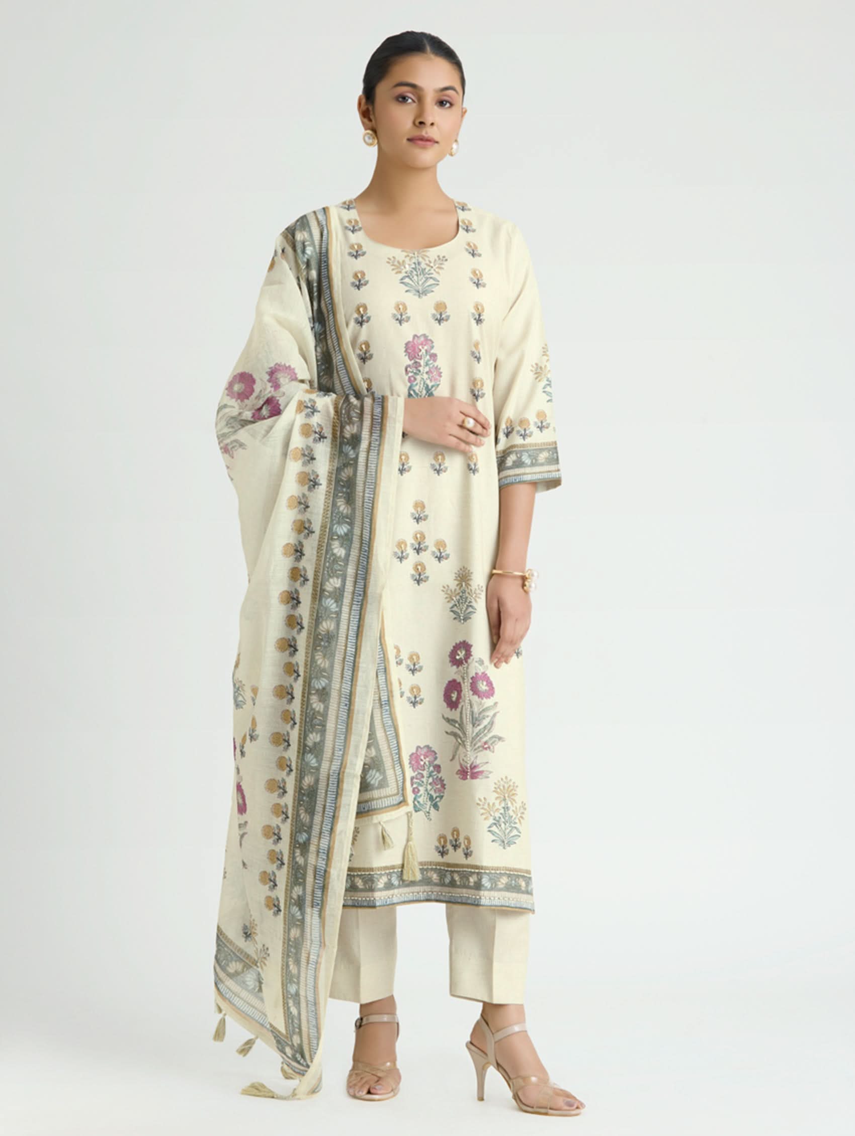 Woman wearing a cream-colored traditional outfit with floral embroidery on a white background