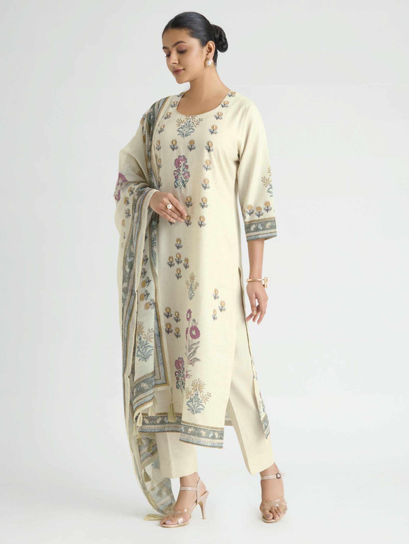 Woman wearing a cream-colored traditional outfit with floral patterns on a white background