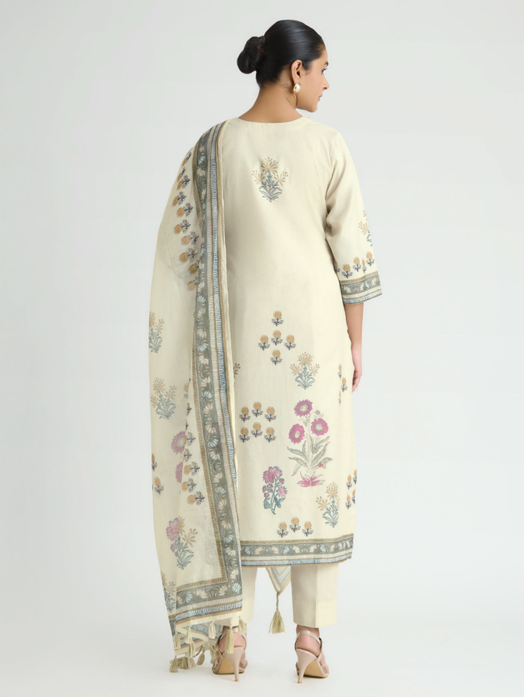 Woman wearing a cream-colored embroidered outfit with a white background