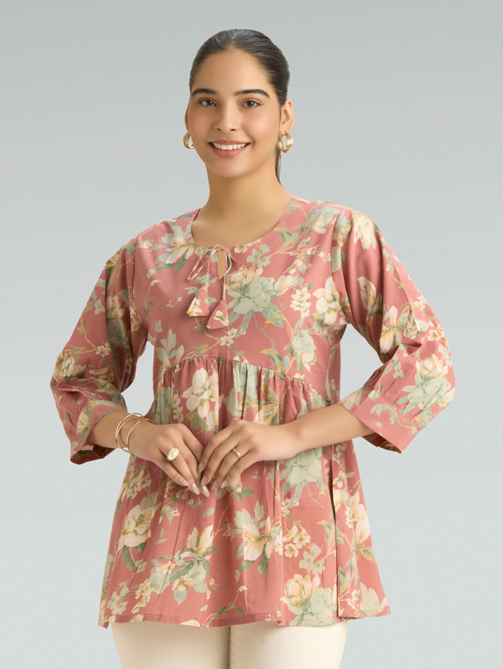 Woman wearing a floral pink top on a gray background