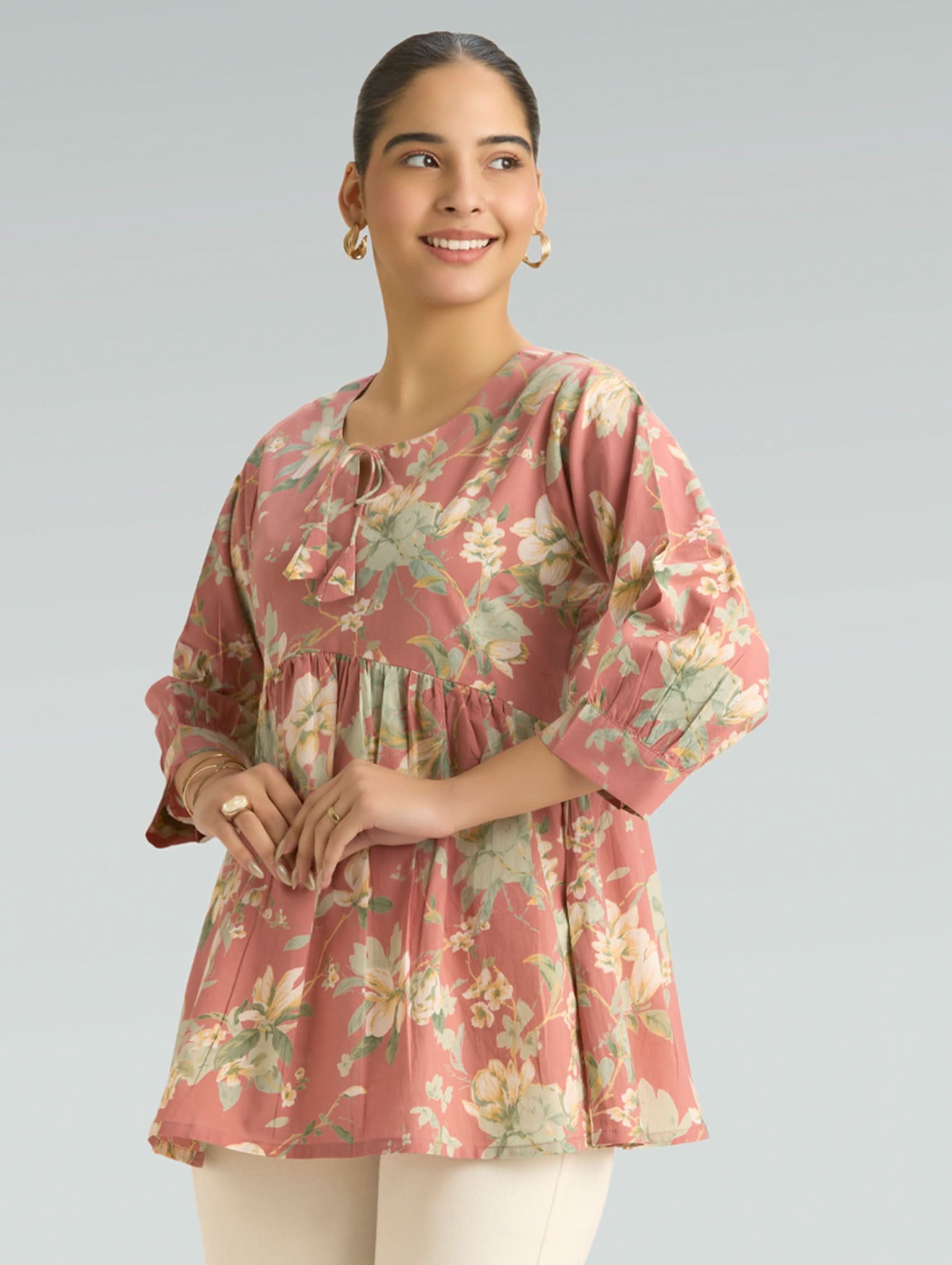 Woman wearing a floral pink top against a plain background