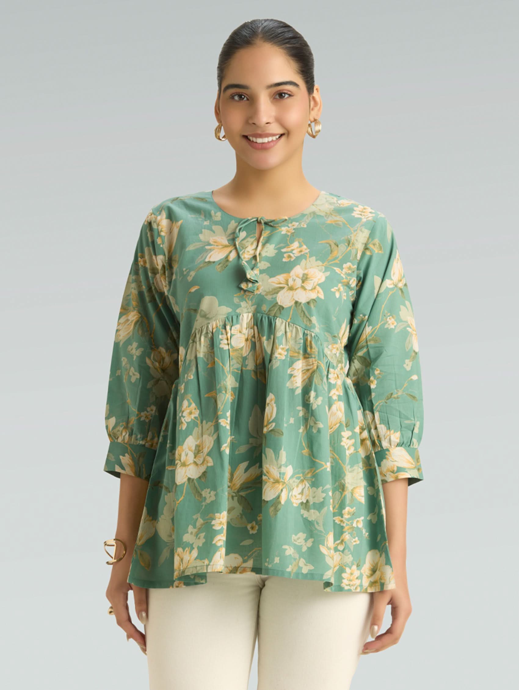 Woman wearing a green floral blouse against a gray background