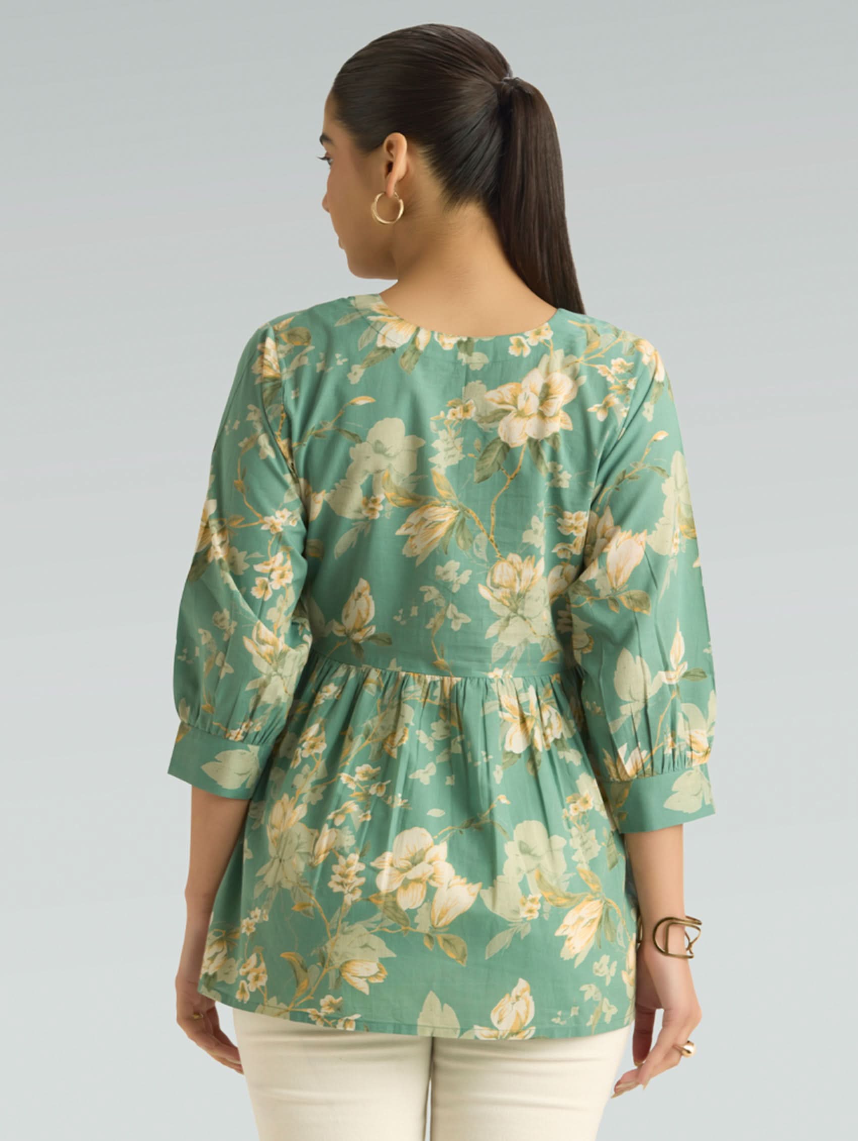 Woman wearing a green floral blouse against a gray background