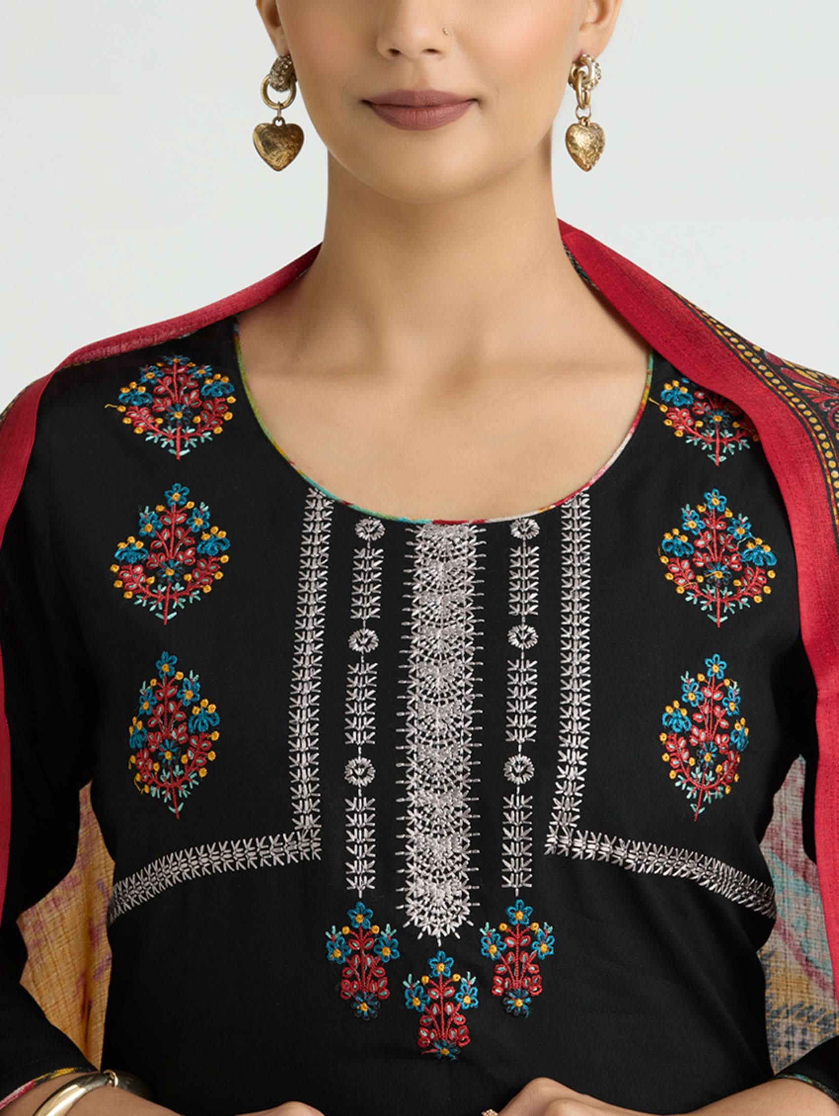 Black embroidered top with colorful patterns and red border worn by a model.