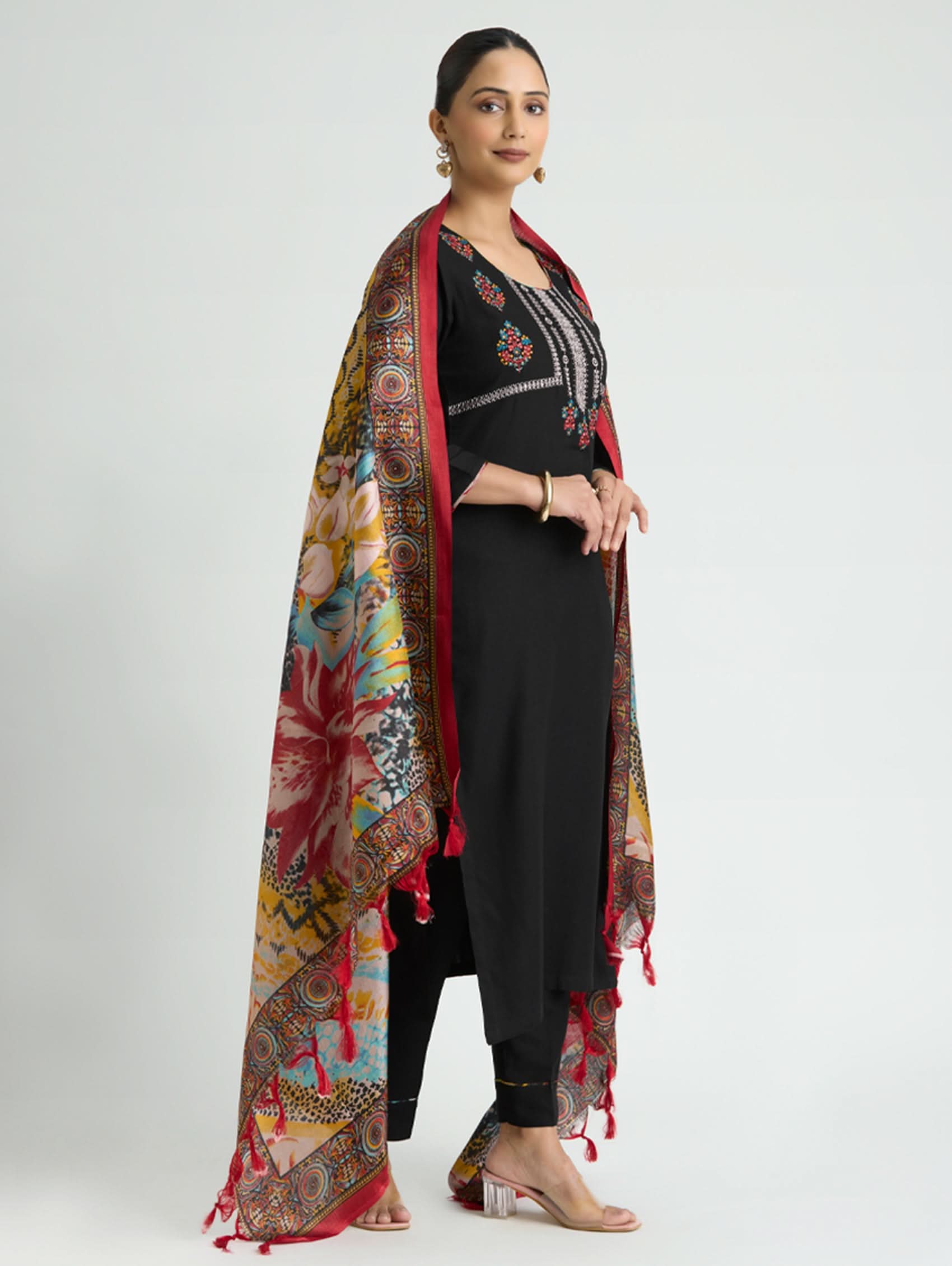 Woman wearing a colorful patterned scarf over a black outfit on a white background