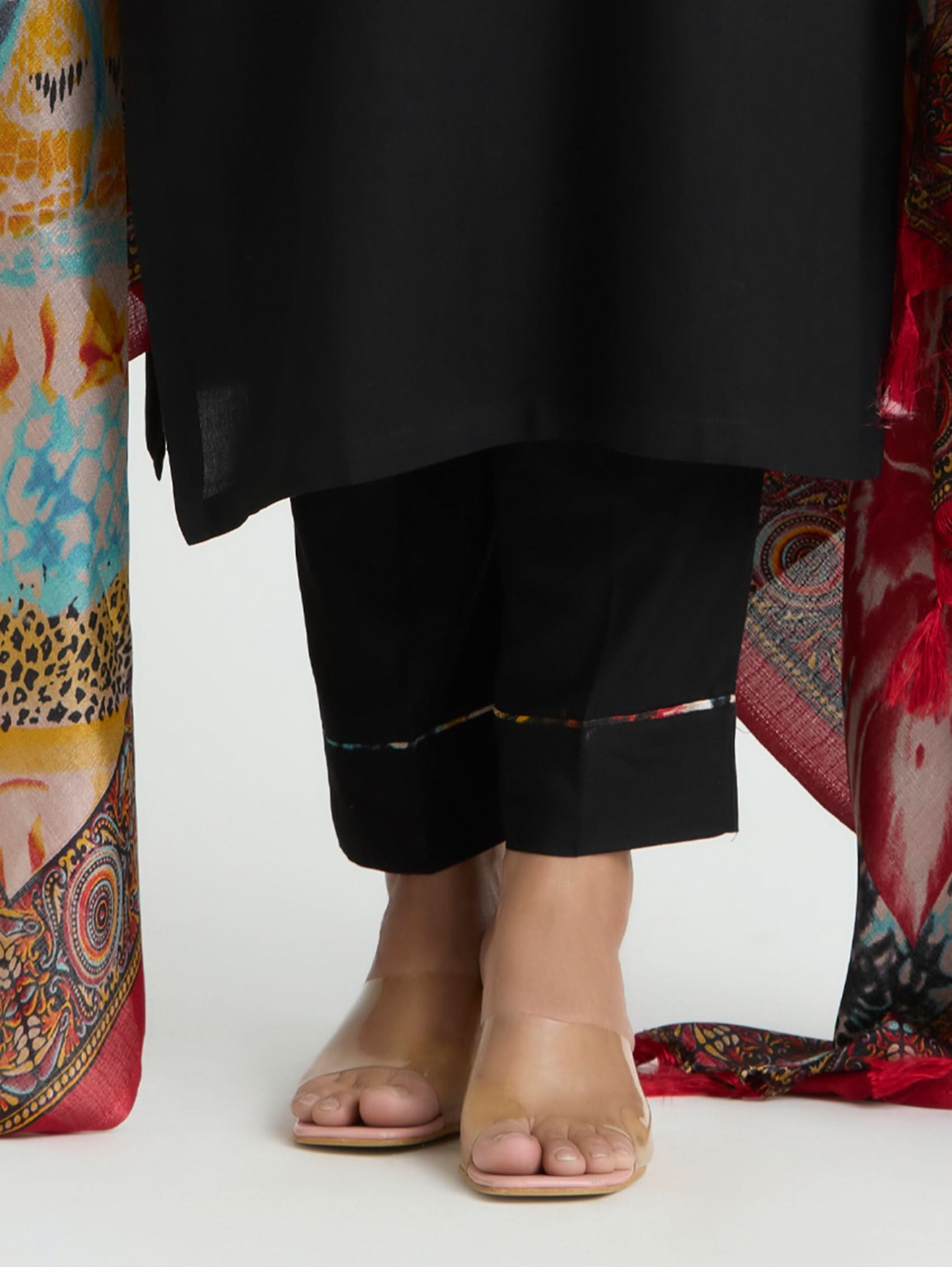Person wearing black pants with colorful patterned fabric draped over them on a white background