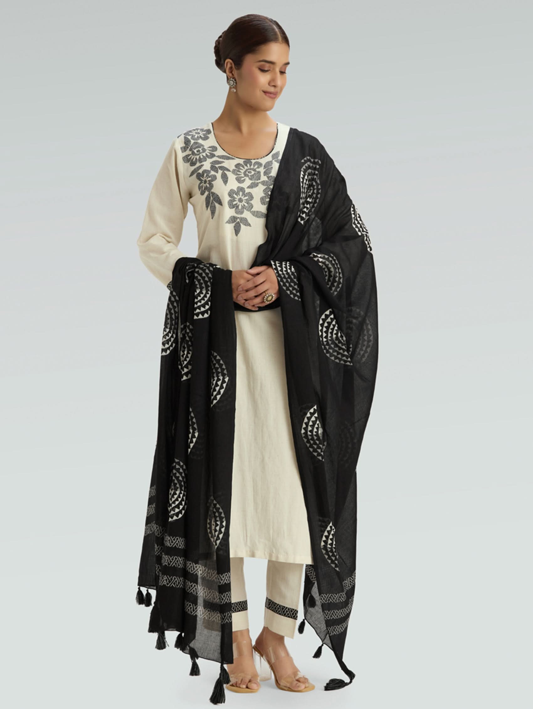 Woman wearing a black and white traditional outfit with a matching dupatta on a light gray background