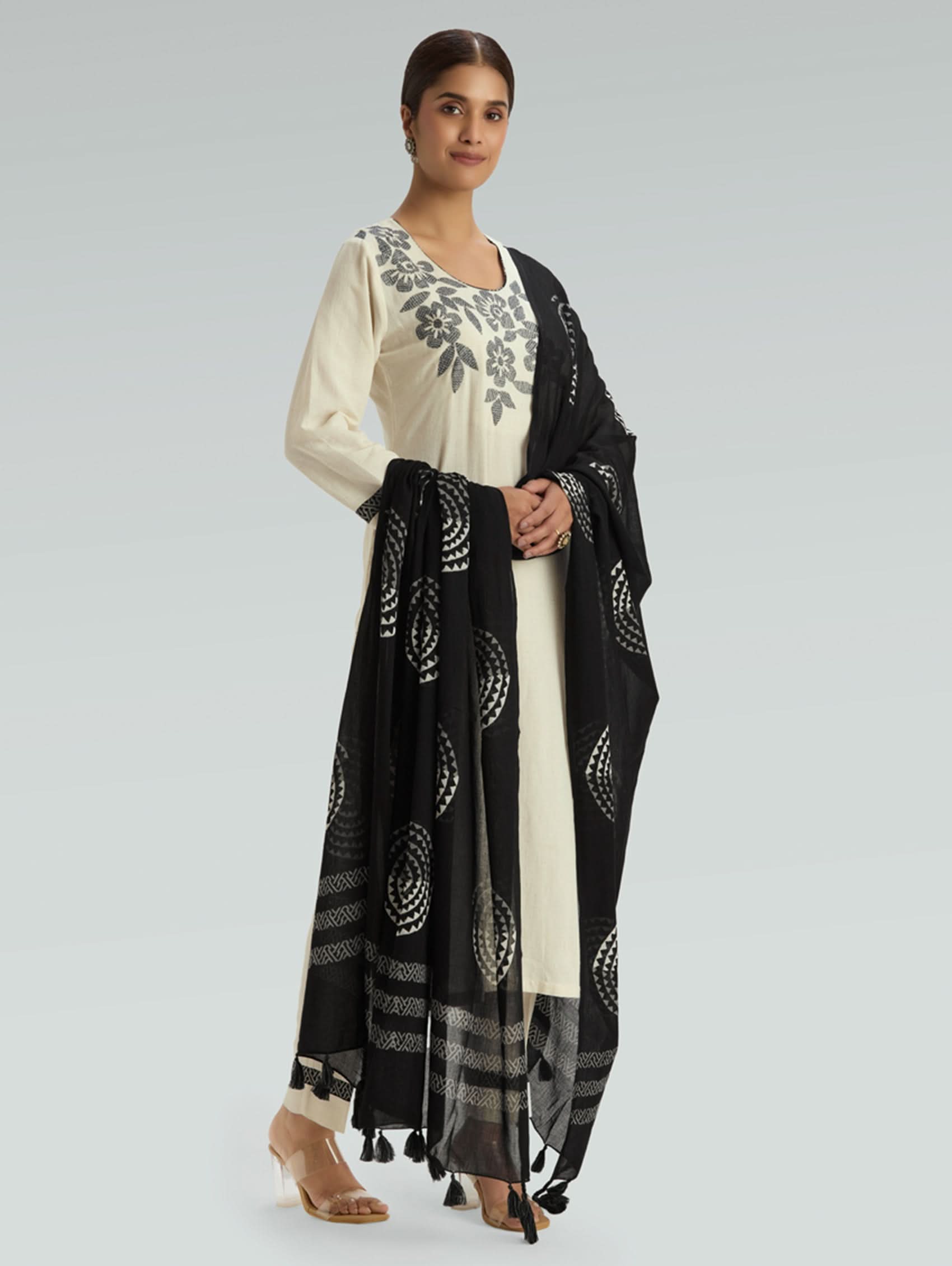 Woman wearing a black and white traditional outfit with a matching dupatta on a light gray background