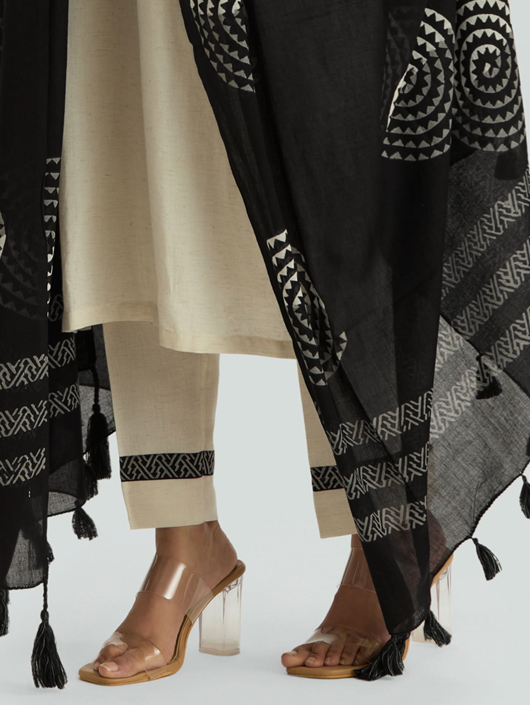 Two people wearing patterned black scarves with tassels on a white background