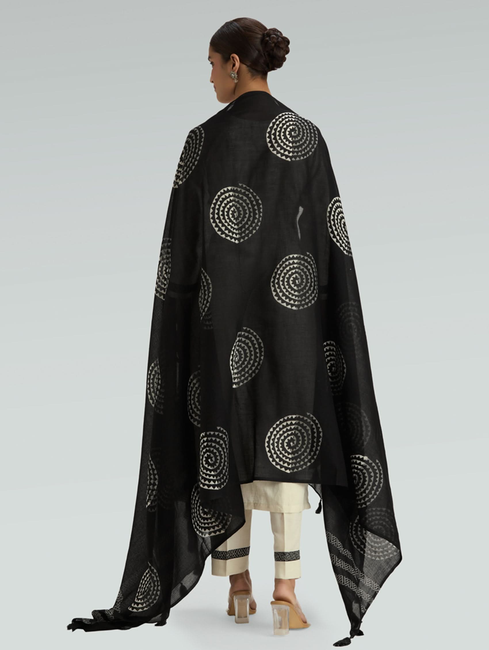Woman wearing a black patterned cape on a light gray background