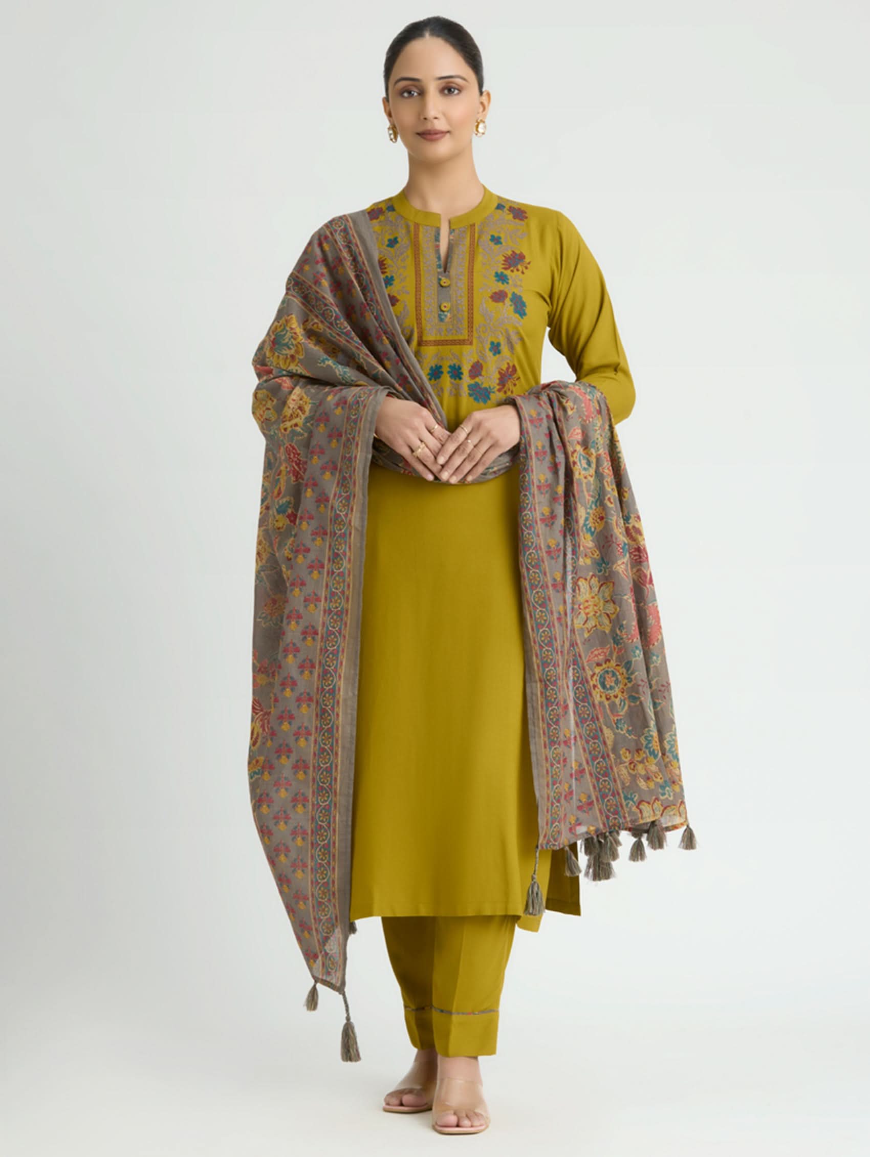 Woman wearing a mustard yellow outfit with a patterned shawl on a white background