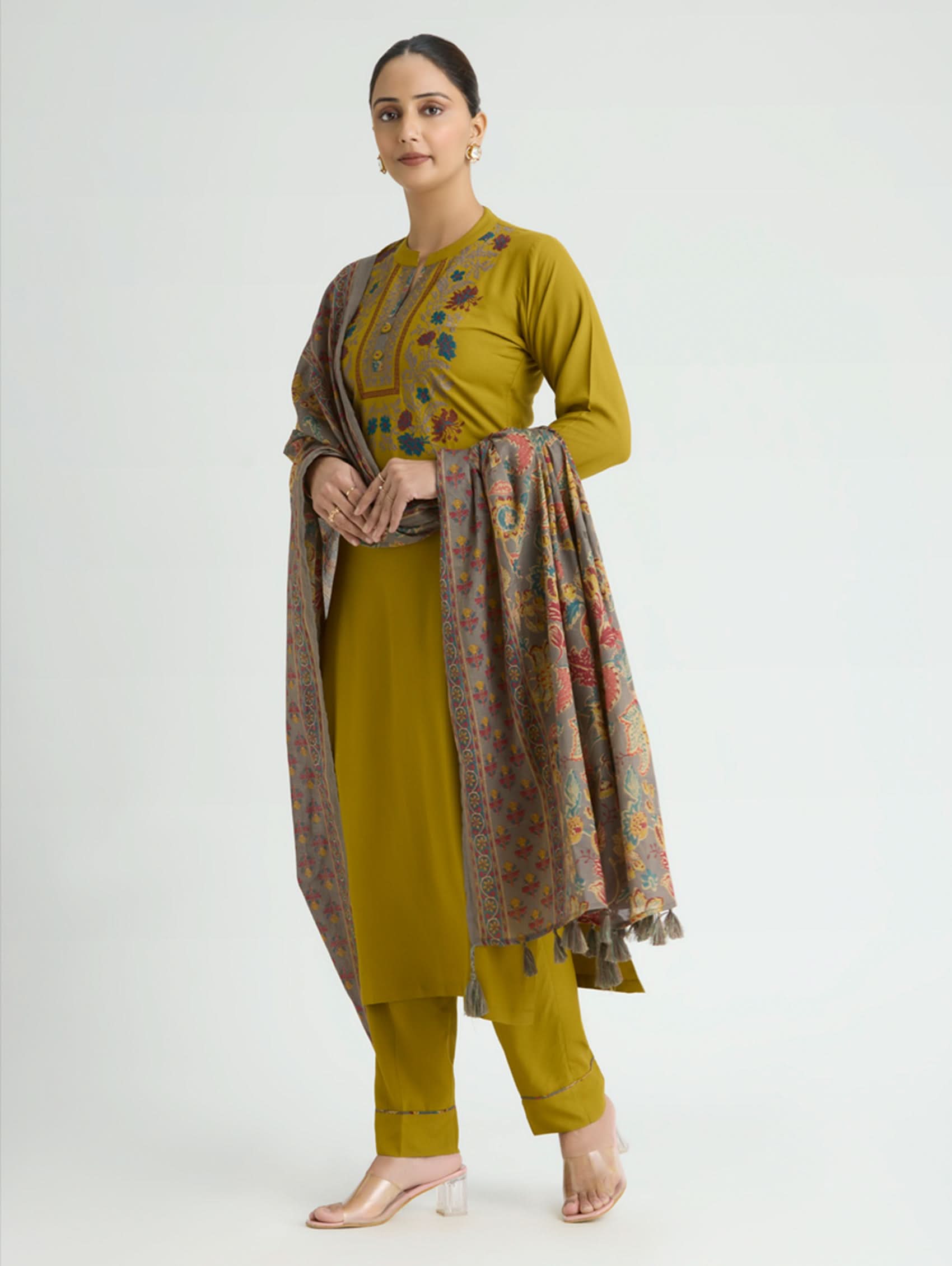 Woman wearing a mustard yellow traditional outfit with a patterned scarf on a white background