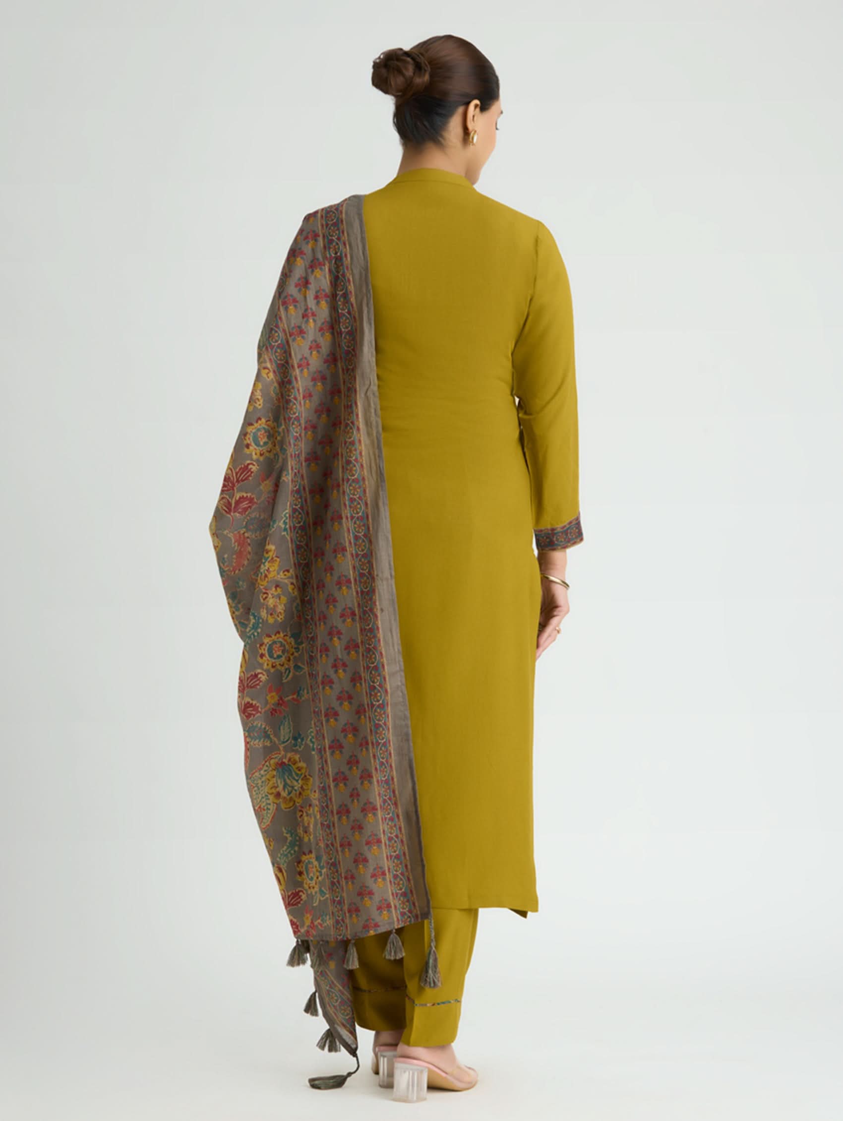 Woman wearing a mustard yellow kurta with a patterned dupatta on a white background