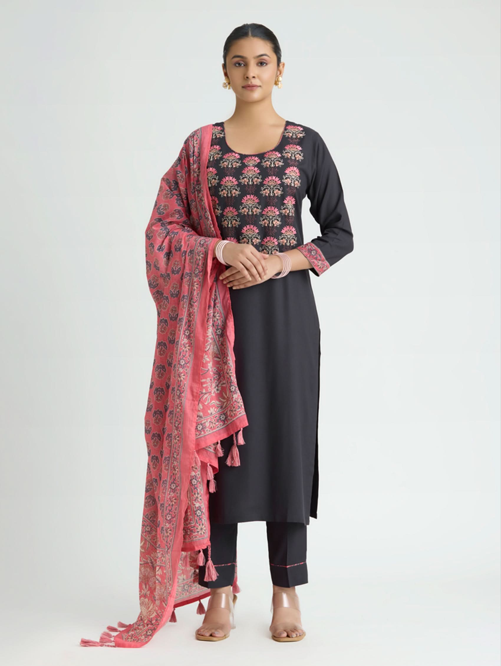 Woman wearing a black outfit with a pink floral dupatta on a white background