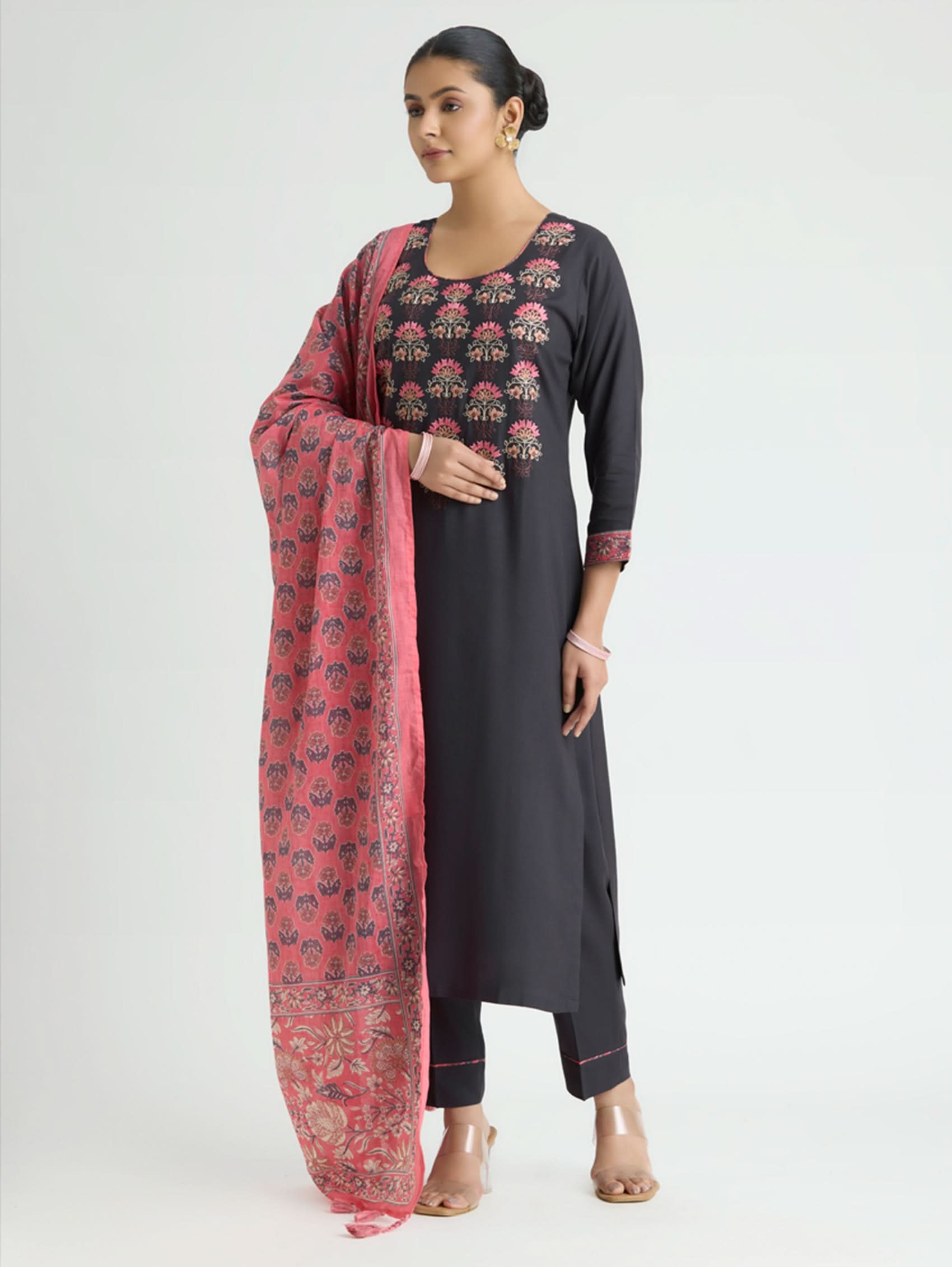 Woman wearing a black kurta with floral patterns and a red dupatta on a white background