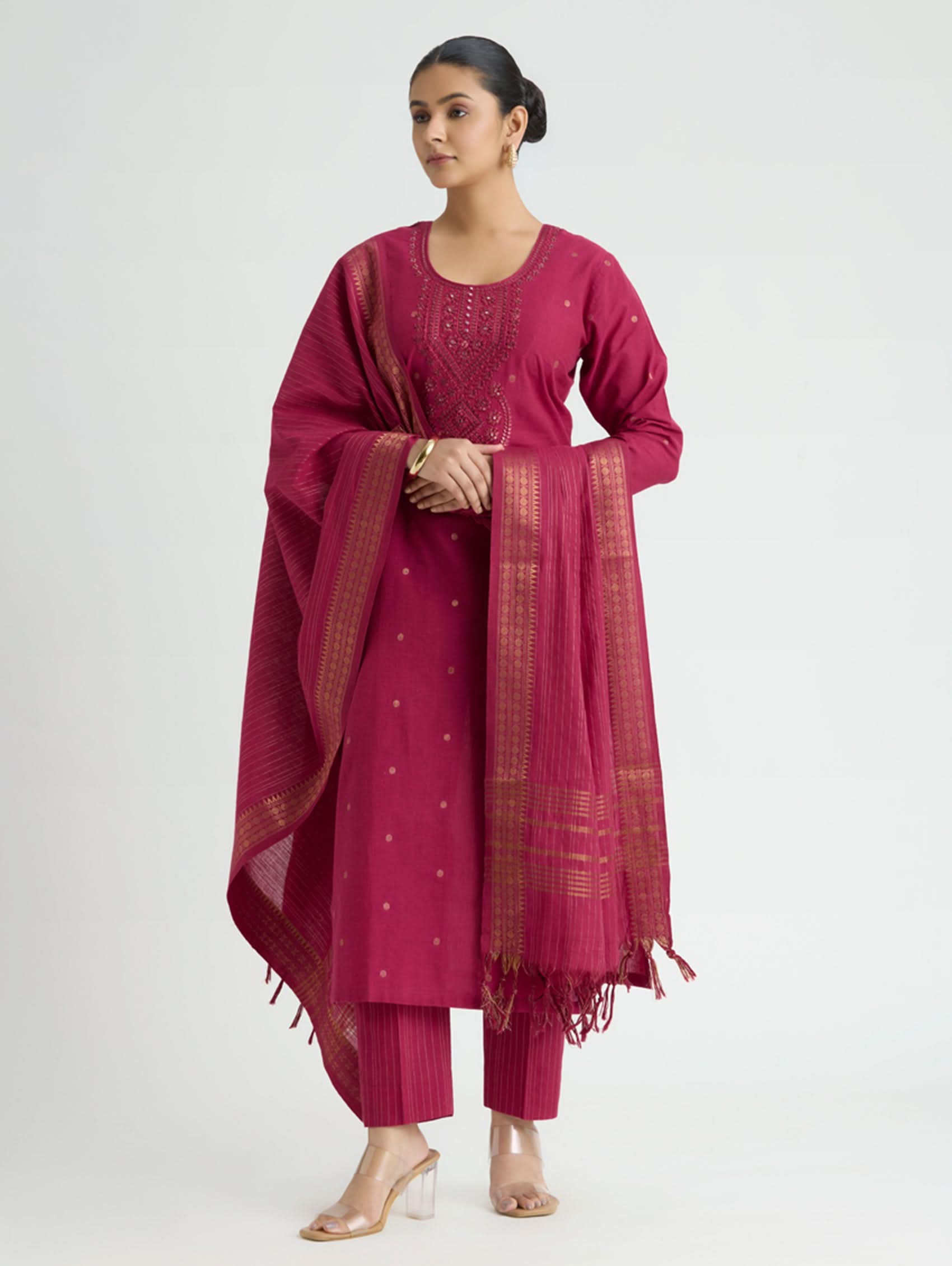 Woman wearing a magenta traditional outfit with a dupatta on a white background