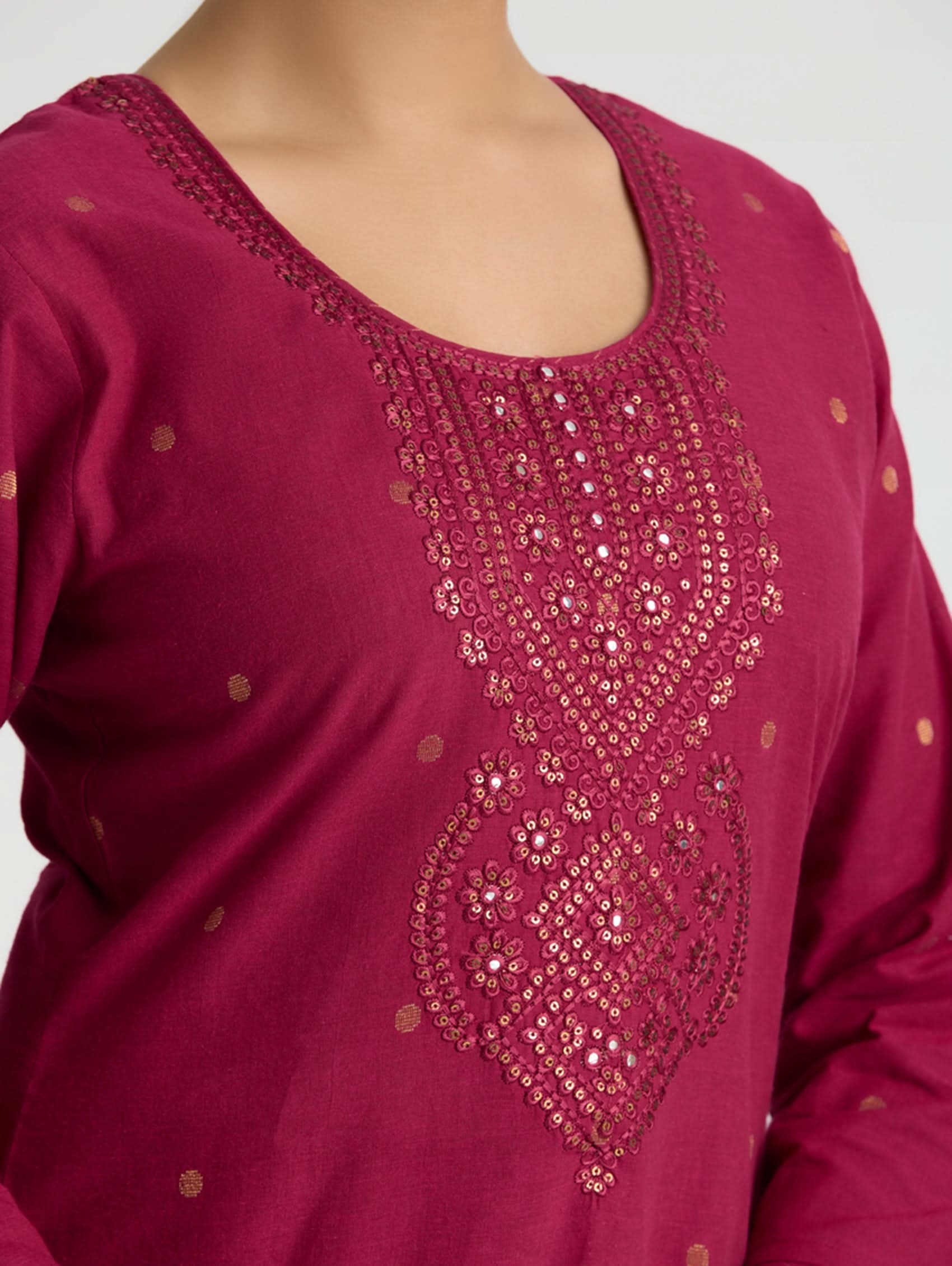 Maroon top with intricate gold embroidery on a plain background