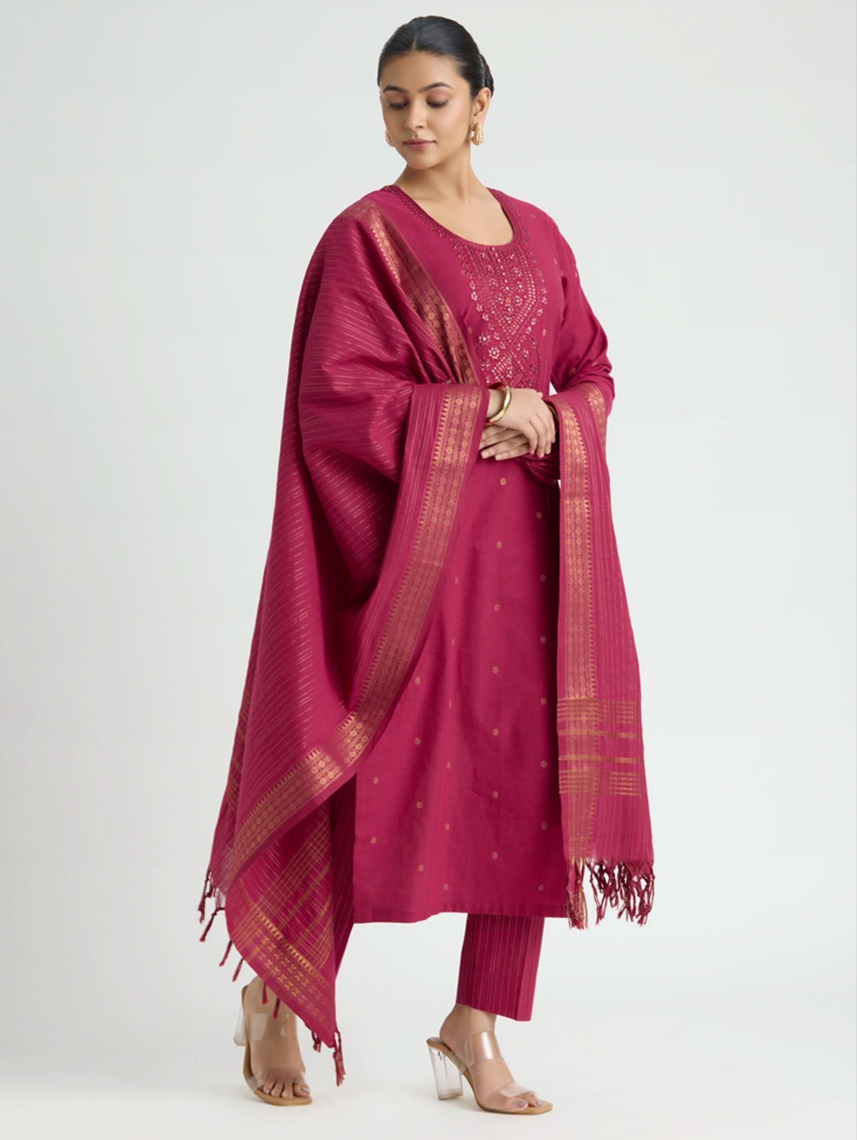 Woman wearing a magenta traditional outfit with a matching dupatta on a white background