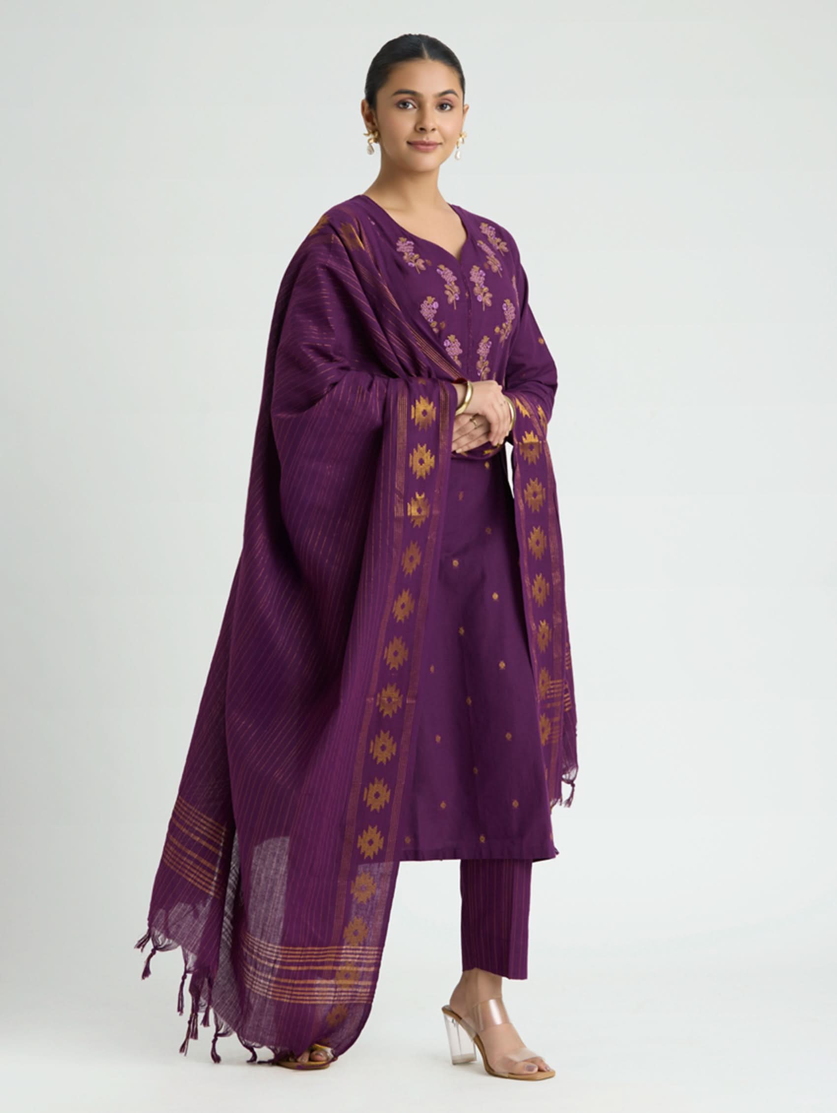 Woman wearing a purple traditional outfit with a matching dupatta on a white background