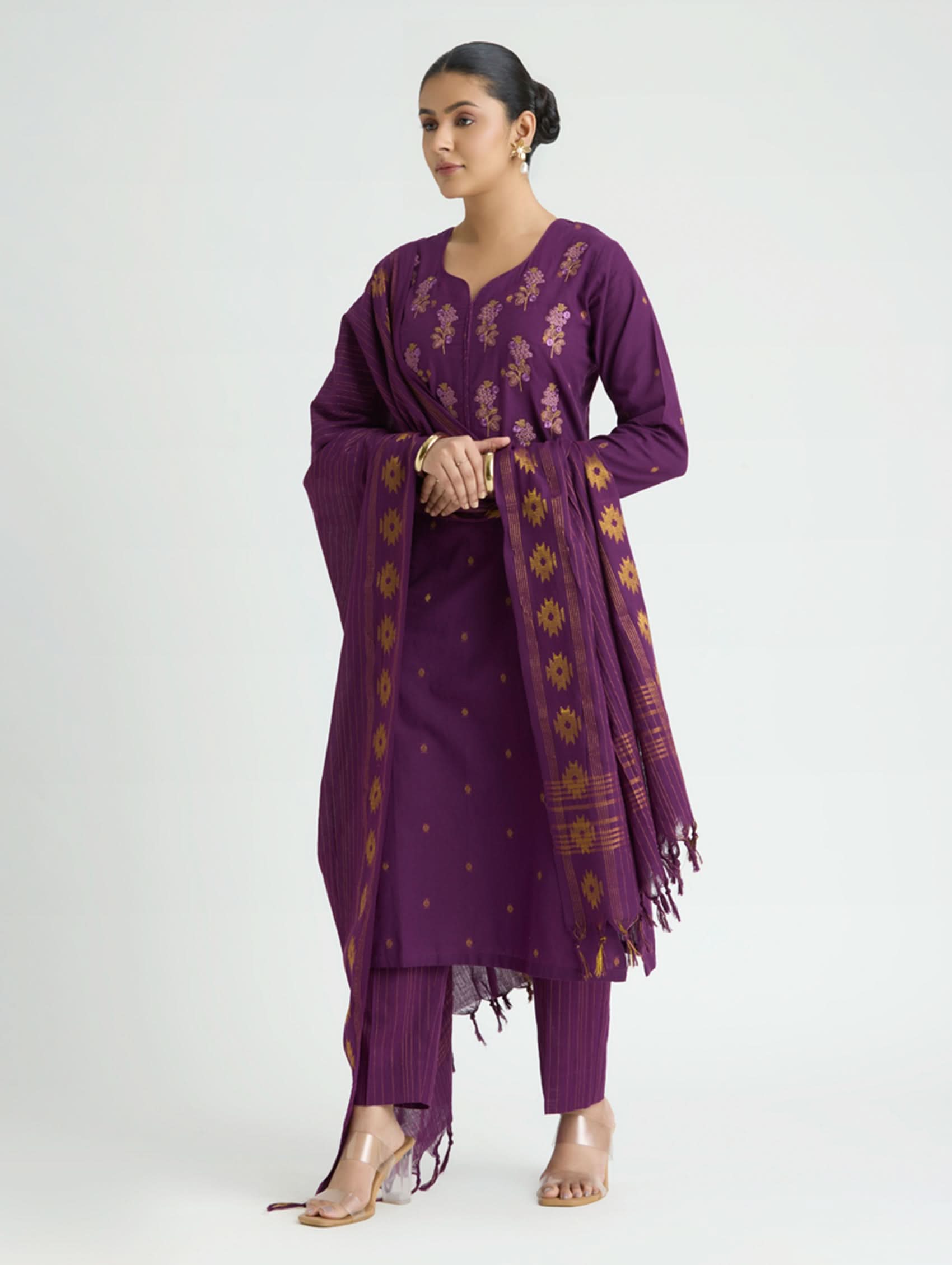 Woman wearing a purple traditional outfit with floral patterns on a white background