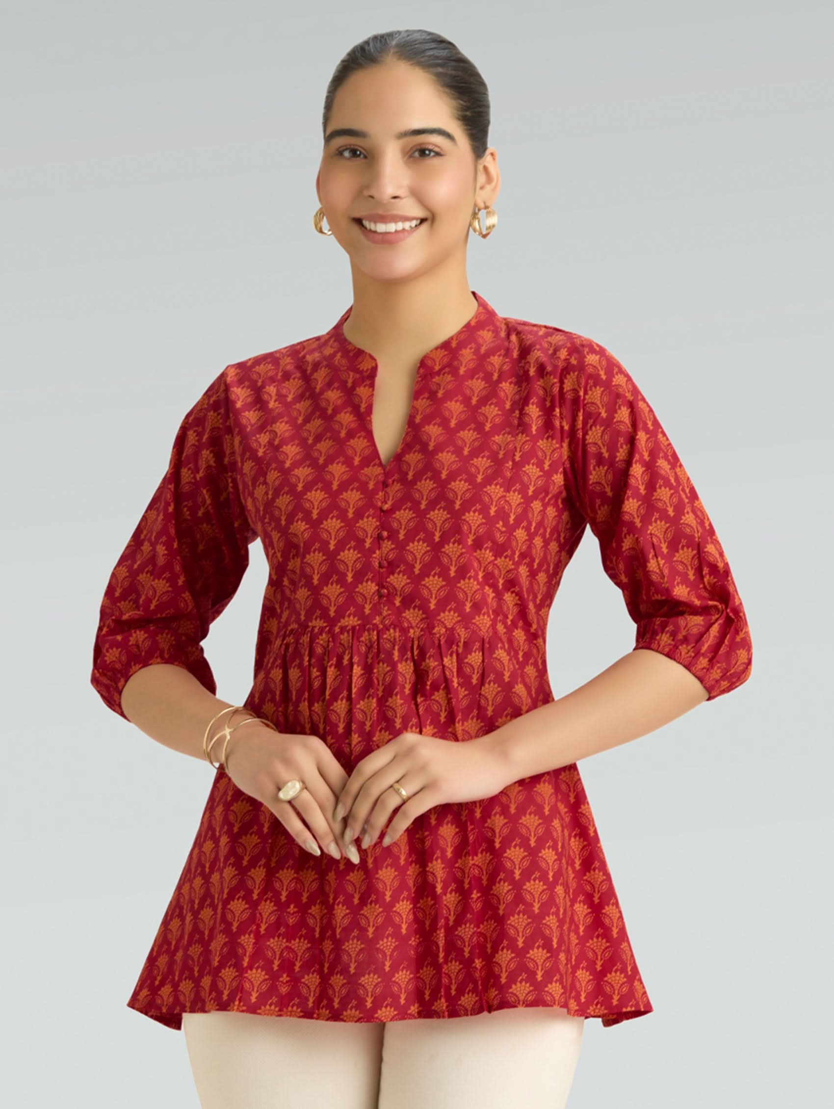 Woman wearing a red patterned top on a gray background
