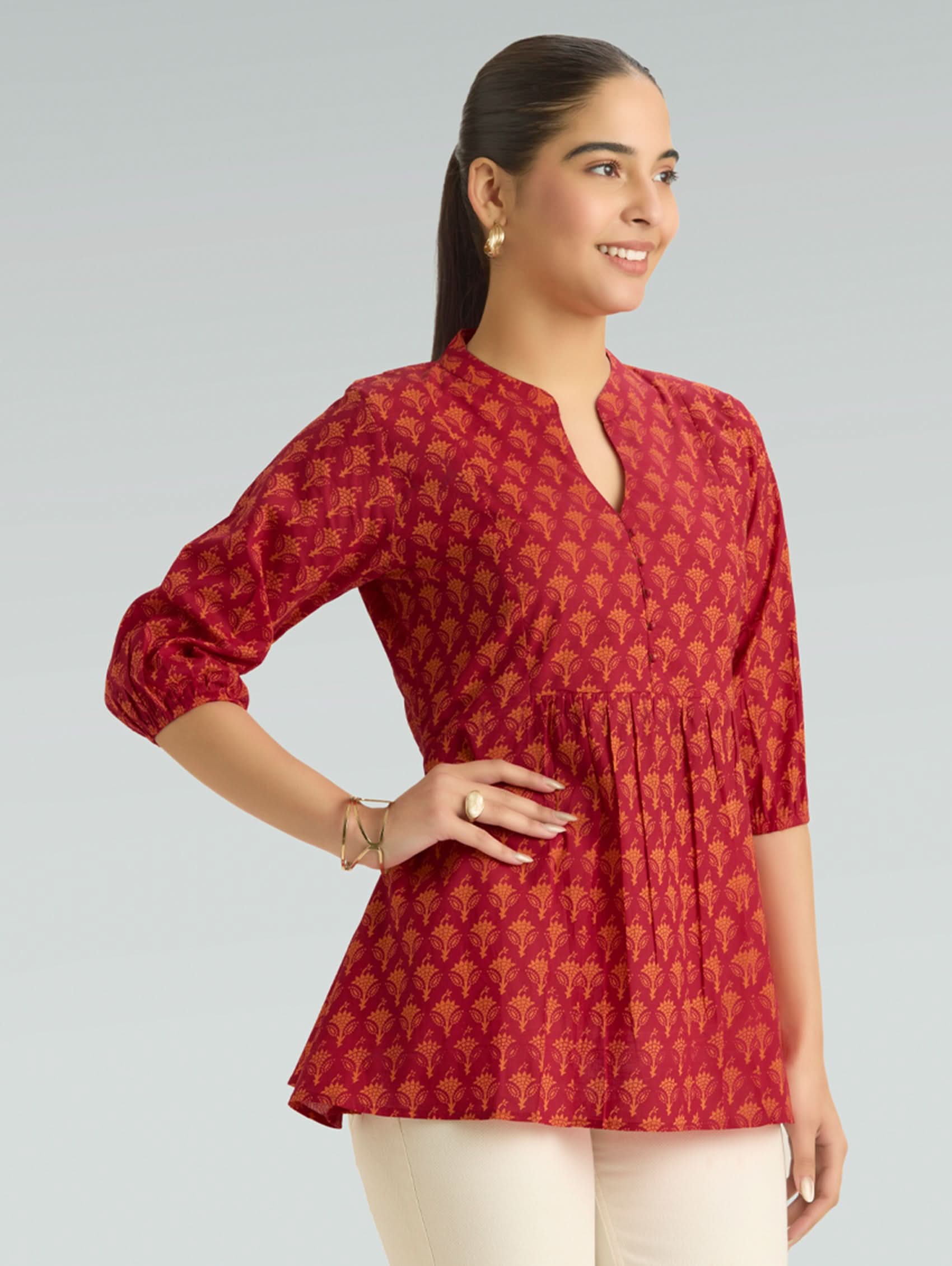 Woman wearing a red patterned top against a gray background