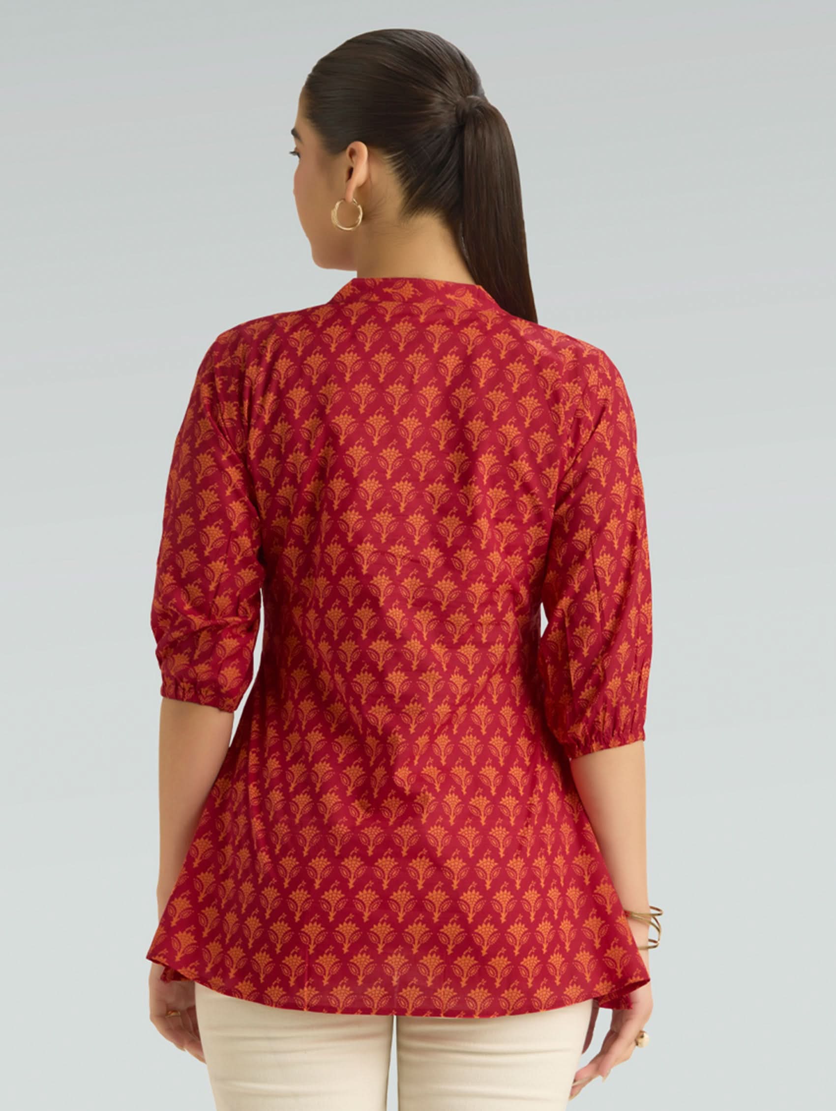 Woman wearing a red patterned top on a gray background