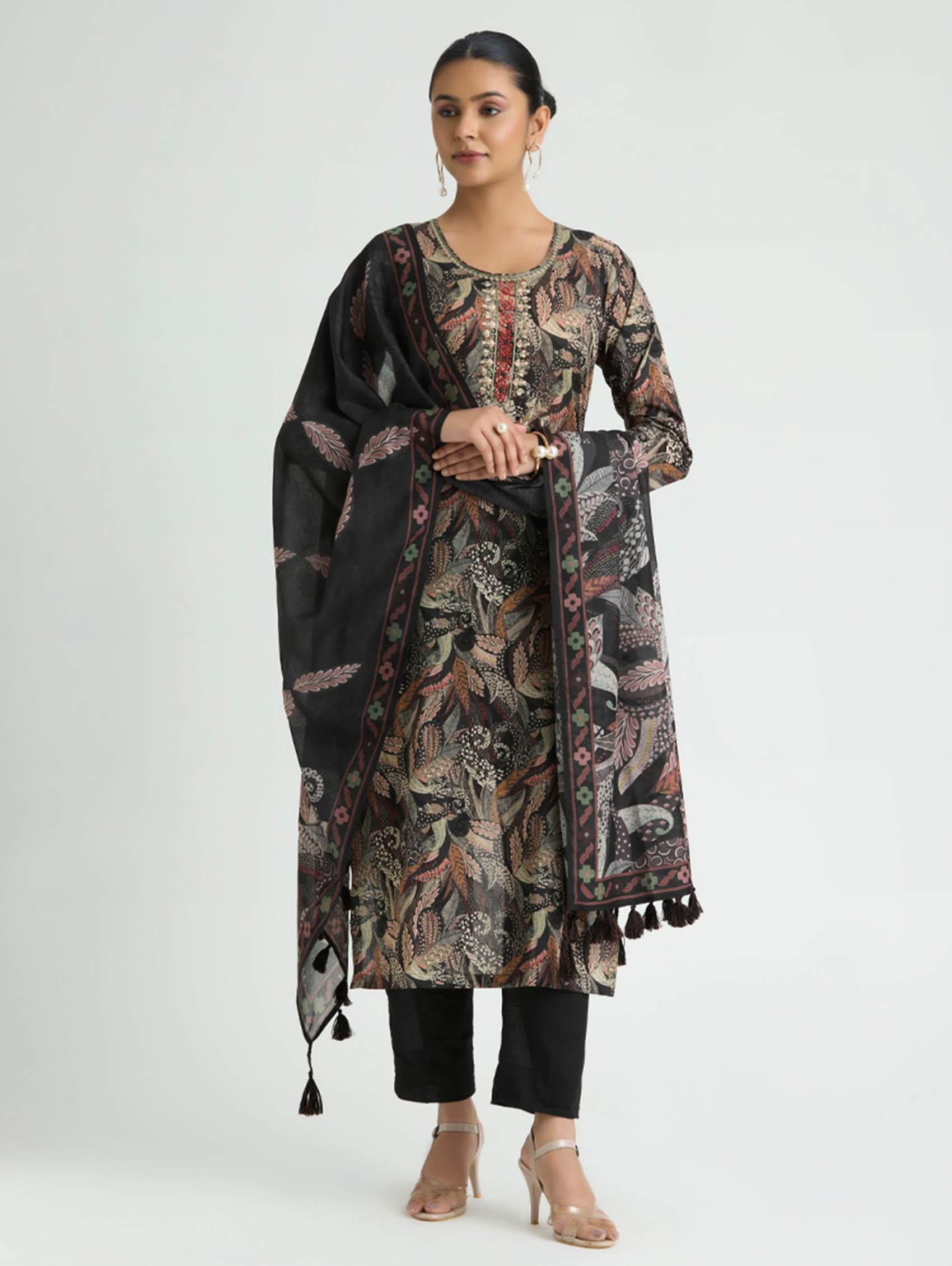 Woman wearing a floral patterned kurta with a black dupatta on a white background