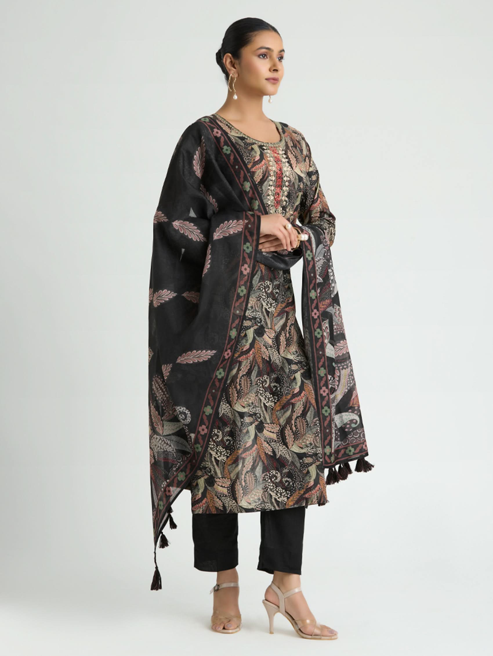 Woman wearing a floral patterned outfit with a black shawl on a white background