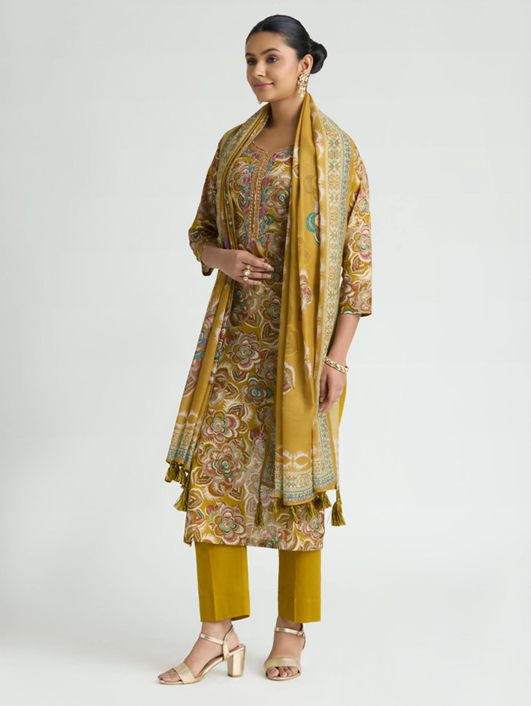 Woman wearing a mustard yellow traditional outfit with a matching dupatta on a white background