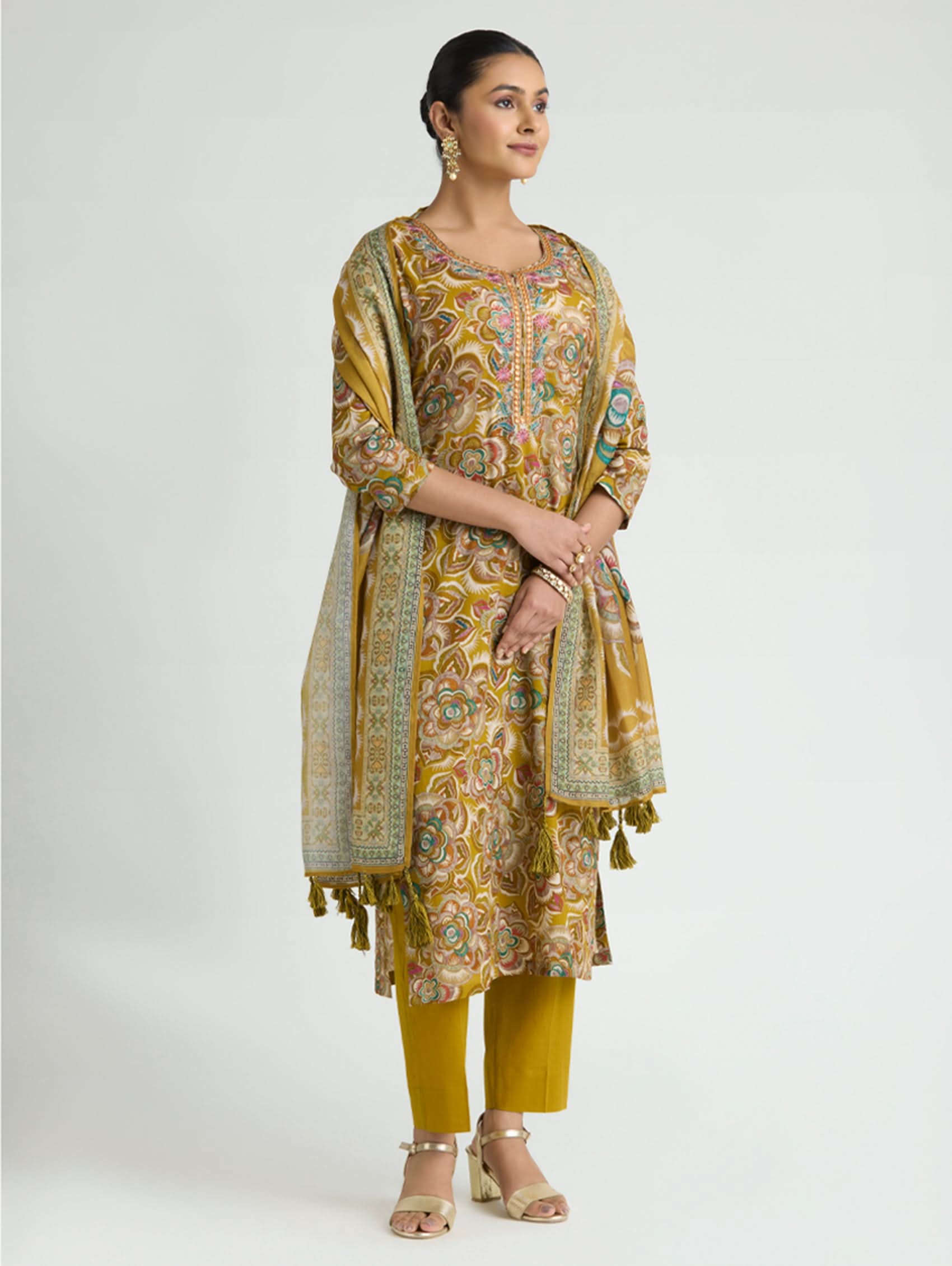 Woman wearing a yellow and green traditional outfit with a matching dupatta on a white background