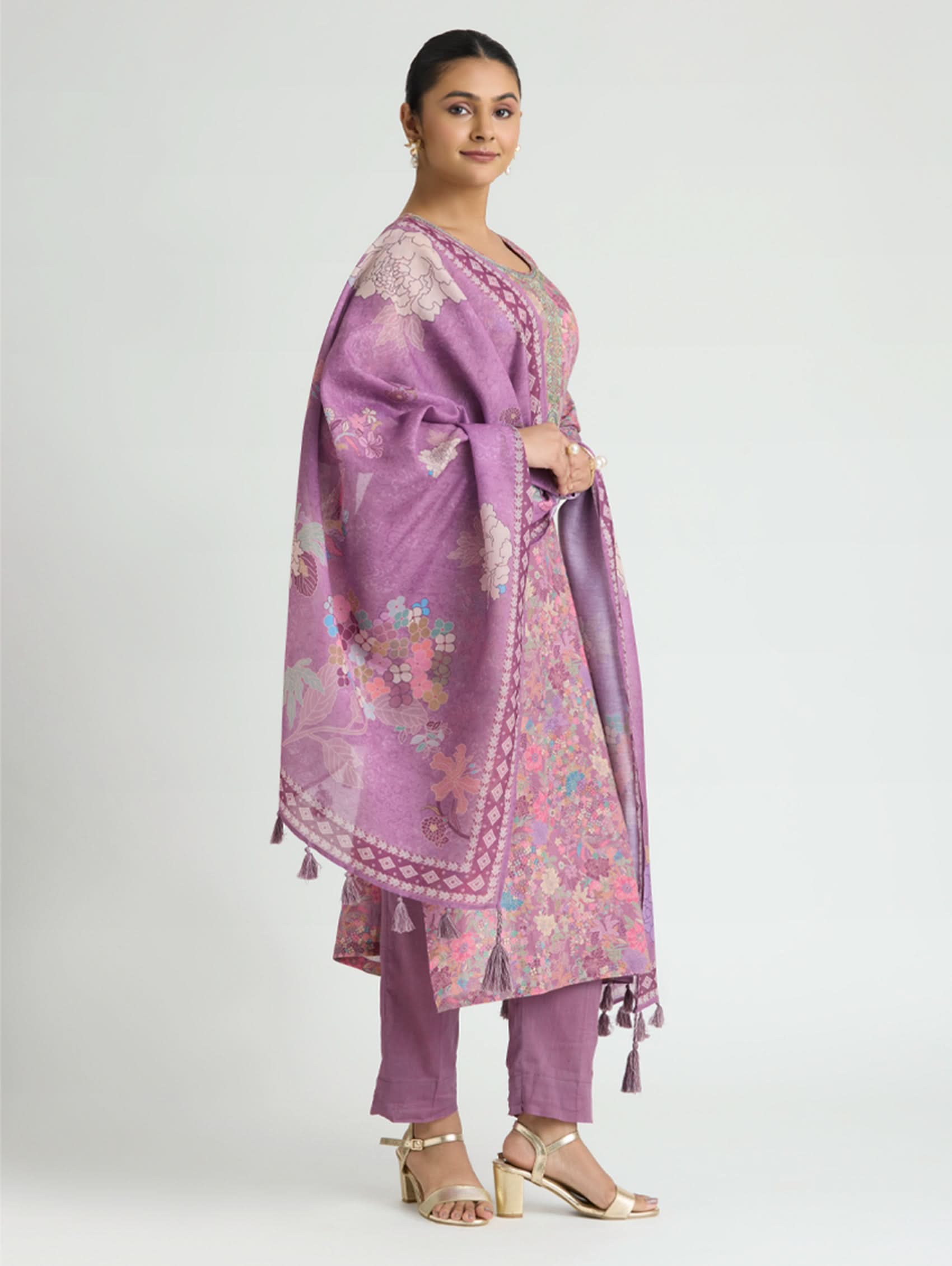 Woman wearing a purple floral outfit with a matching dupatta on a white background