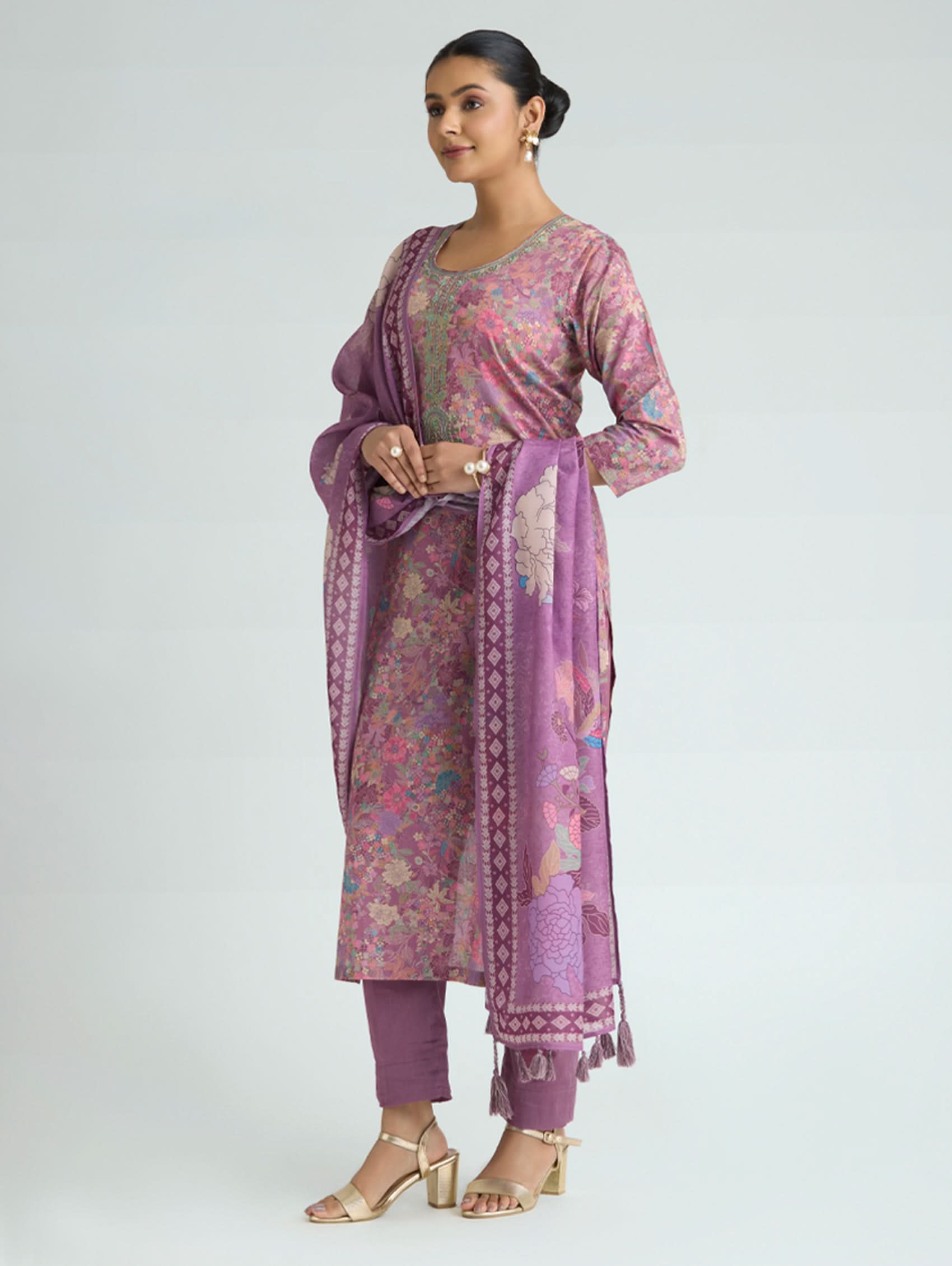 Woman wearing a pink and purple traditional outfit with a matching dupatta on a white background